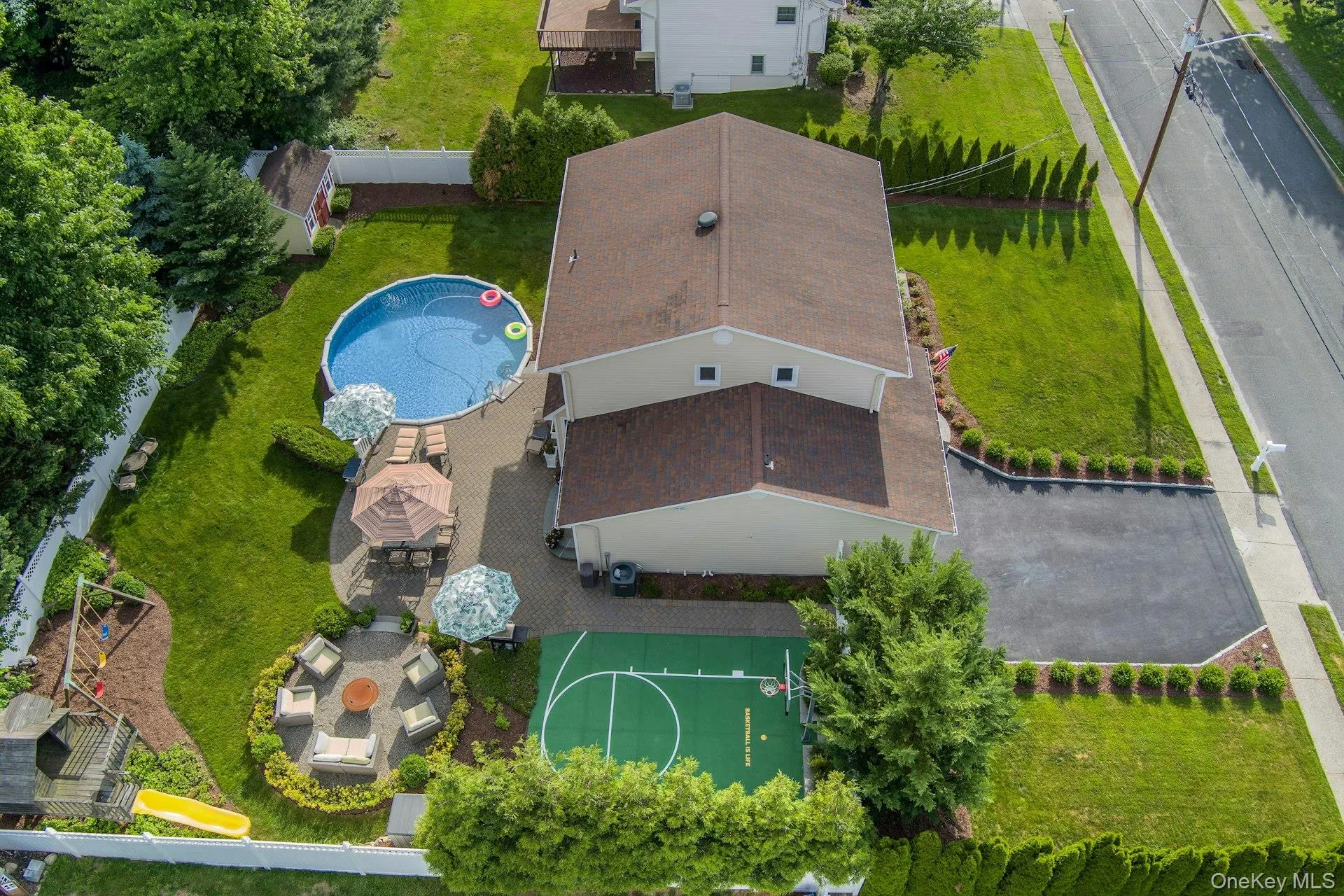 Expansive backyard with an above-ground heated pool, paved patio, and multi-sport court Expansive backyard with an above-ground heated pool, paved patio, and multi-sport court