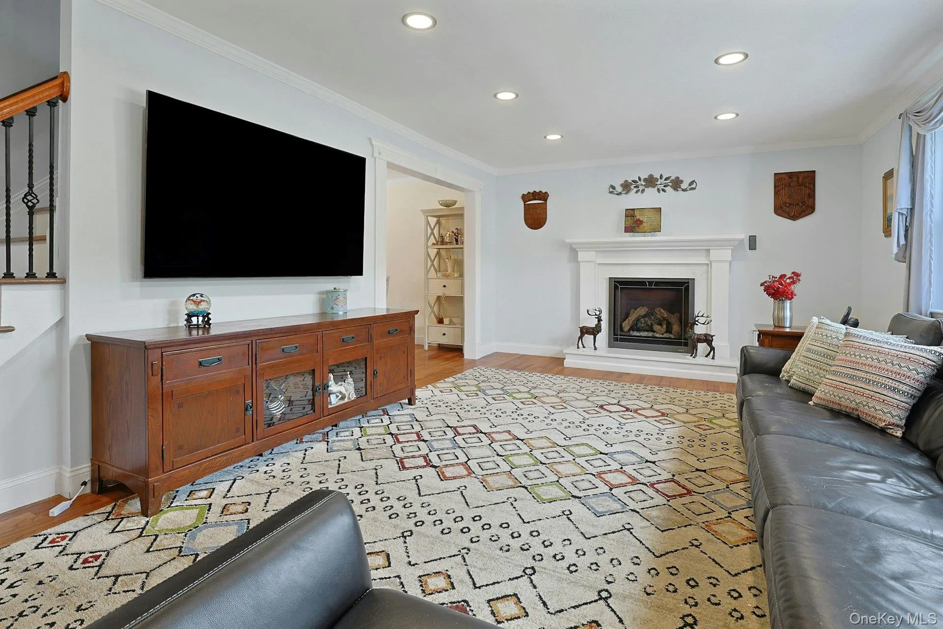 Living area featuring a fireplace with a white mantel, recessed lighting, and wood-finish flooring Living area featuring a fireplace with a white mantel, recessed lighting, and wood-finish flooring