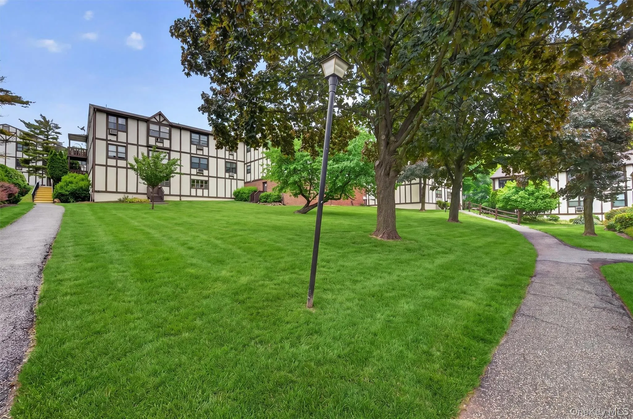 Spacious green lawn with mature trees and paved walking paths Spacious green lawn with mature trees and paved walking paths
