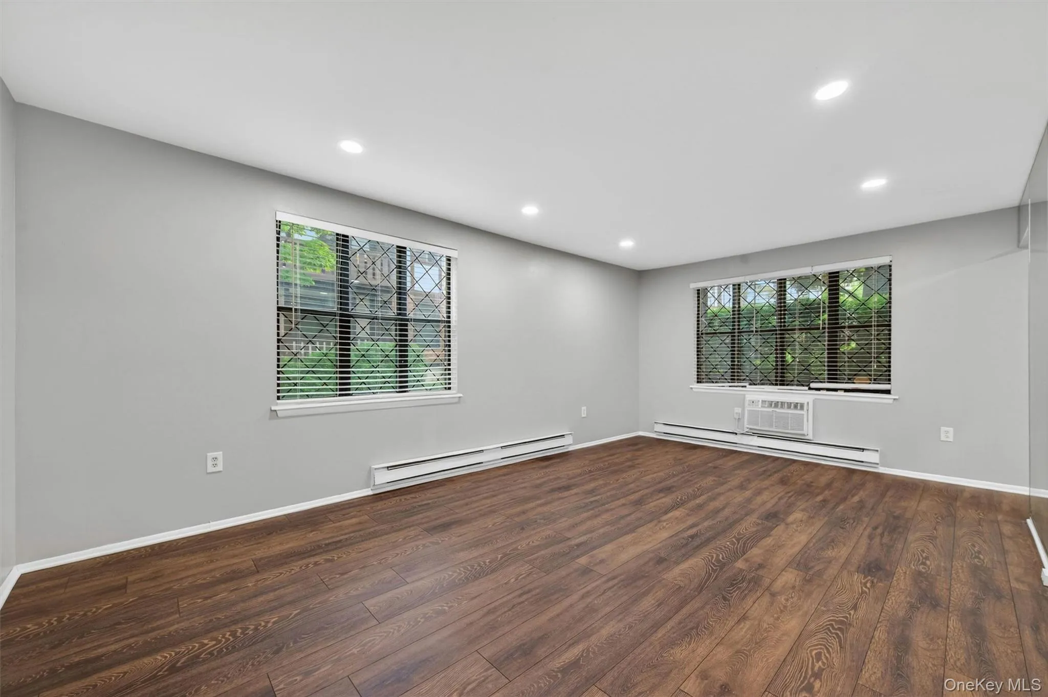 Spacious room featuring wood-finish flooring, recessed lighting, and light gray walls Spacious room featuring wood-finish flooring, recessed lighting, and light gray walls