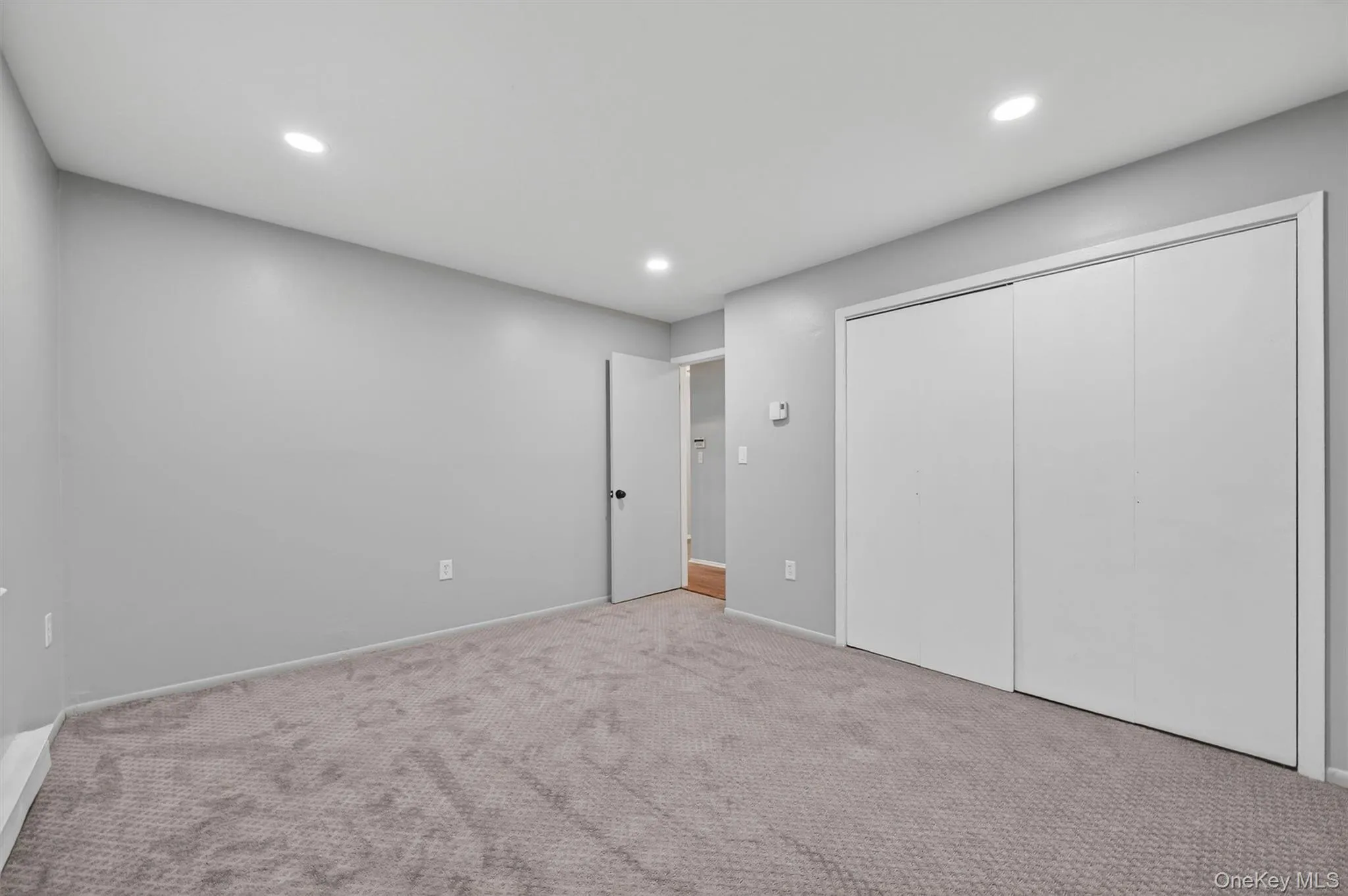 Neutral gray walls with recessed lighting and gray patterned carpeting Neutral gray walls with recessed lighting and gray patterned carpeting