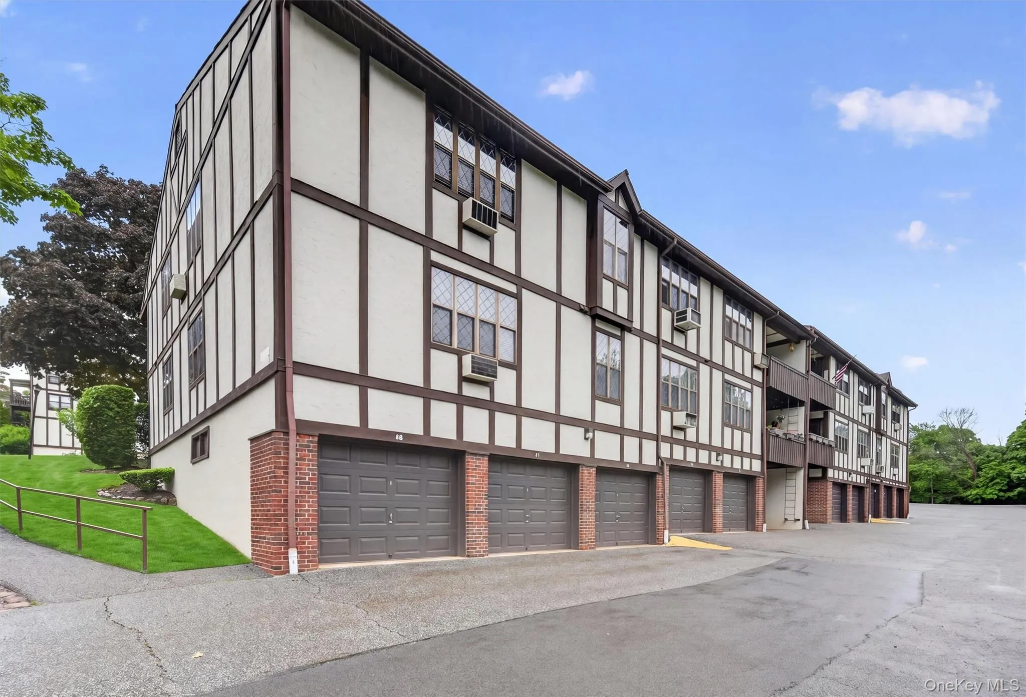 Multi-level residential building featuring Tudor-style architectural elements with white stucco and dark wood-finish trim Multi-level residential building featuring Tudor-style architectural elements with white stucco and dark wood-finish trim
