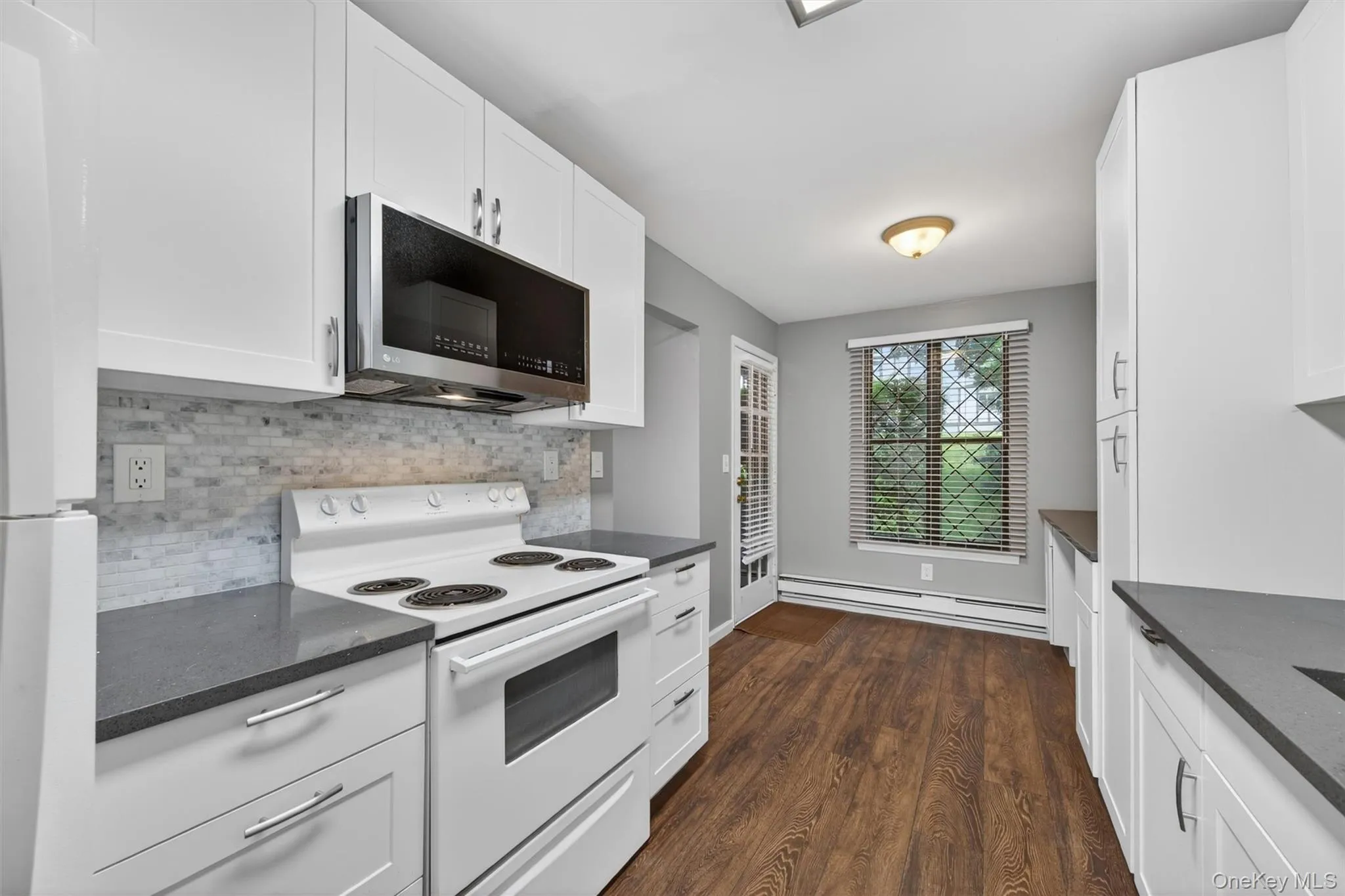 Modern kitchen with white cabinetry and dark countertops Modern kitchen with white cabinetry and dark countertops