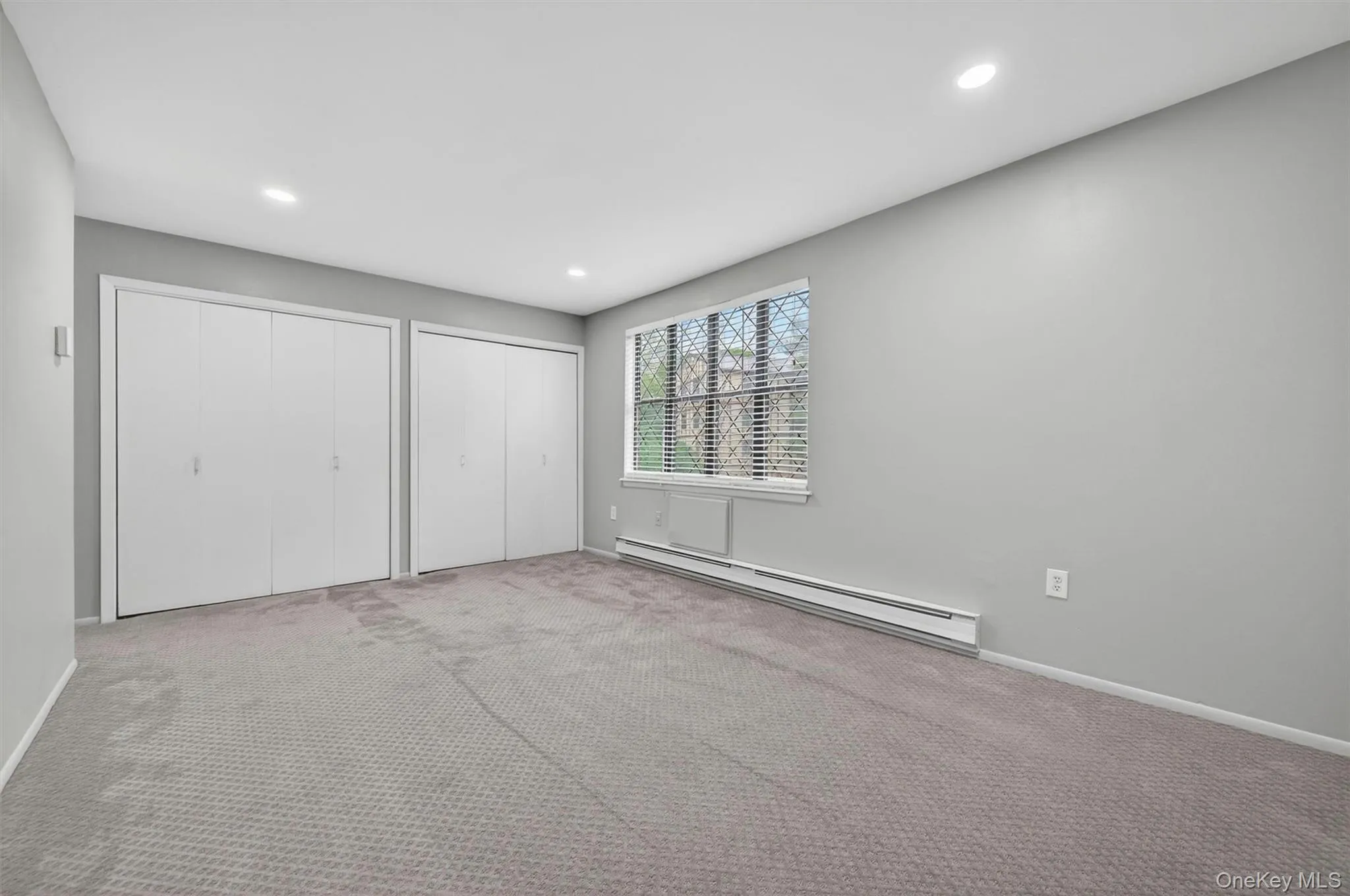 Spacious room featuring neutral carpeting, light gray wall paint, and white trim Spacious room featuring neutral carpeting, light gray wall paint, and white trim