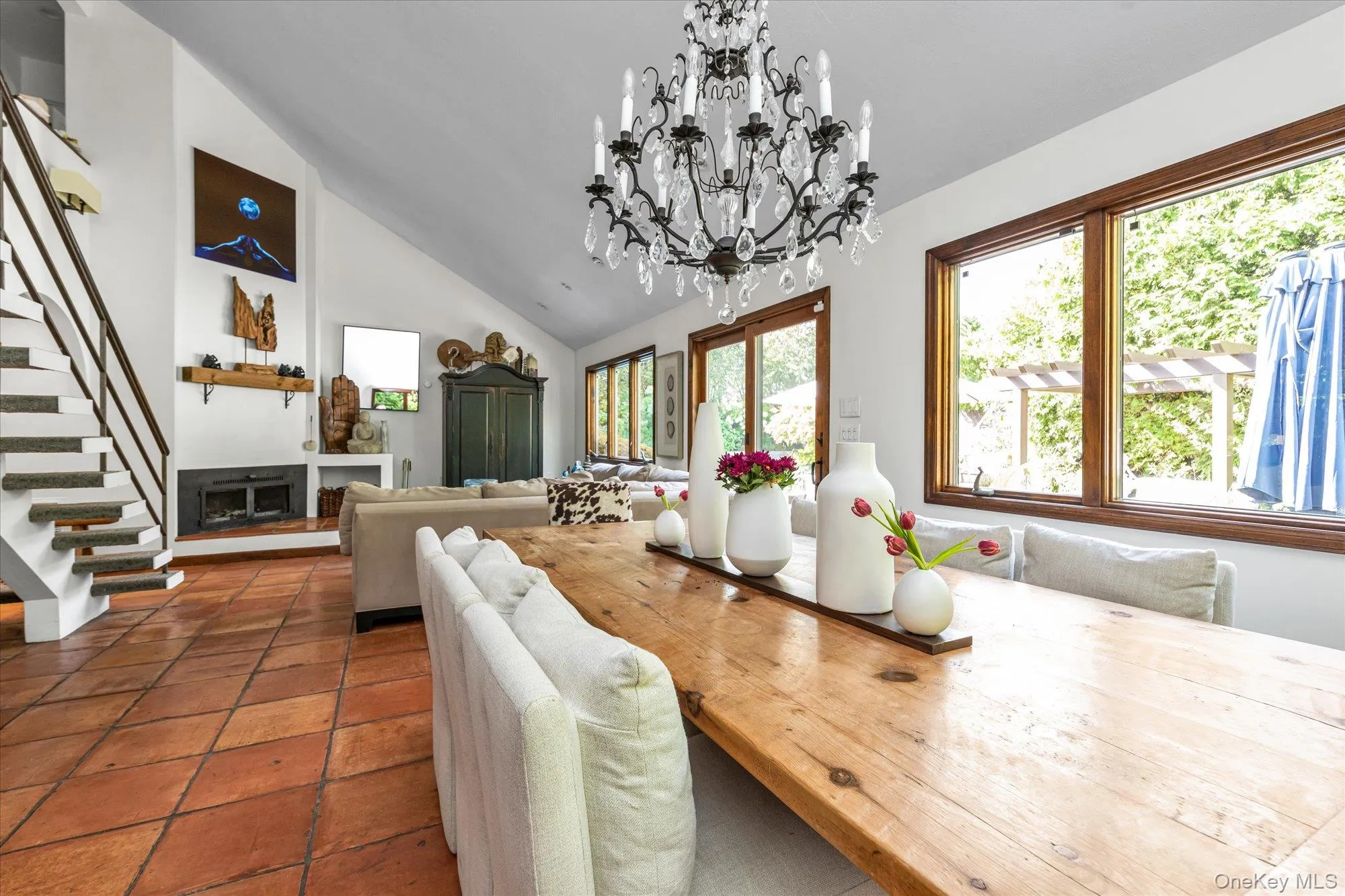 Dining room with a fireplace, a chandelier, high vaulted ceiling, and stairs Dining room with a fireplace, a chandelier, high vaulted ceiling, and stairs