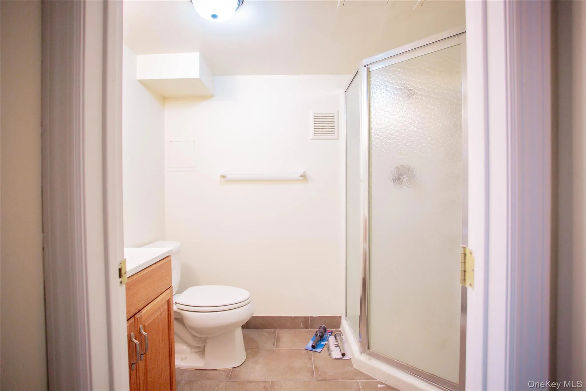 Bathroom with tile patterned floors, vanity, a stall shower, and toilet Bathroom with tile patterned floors, vanity, a stall shower, and toilet
