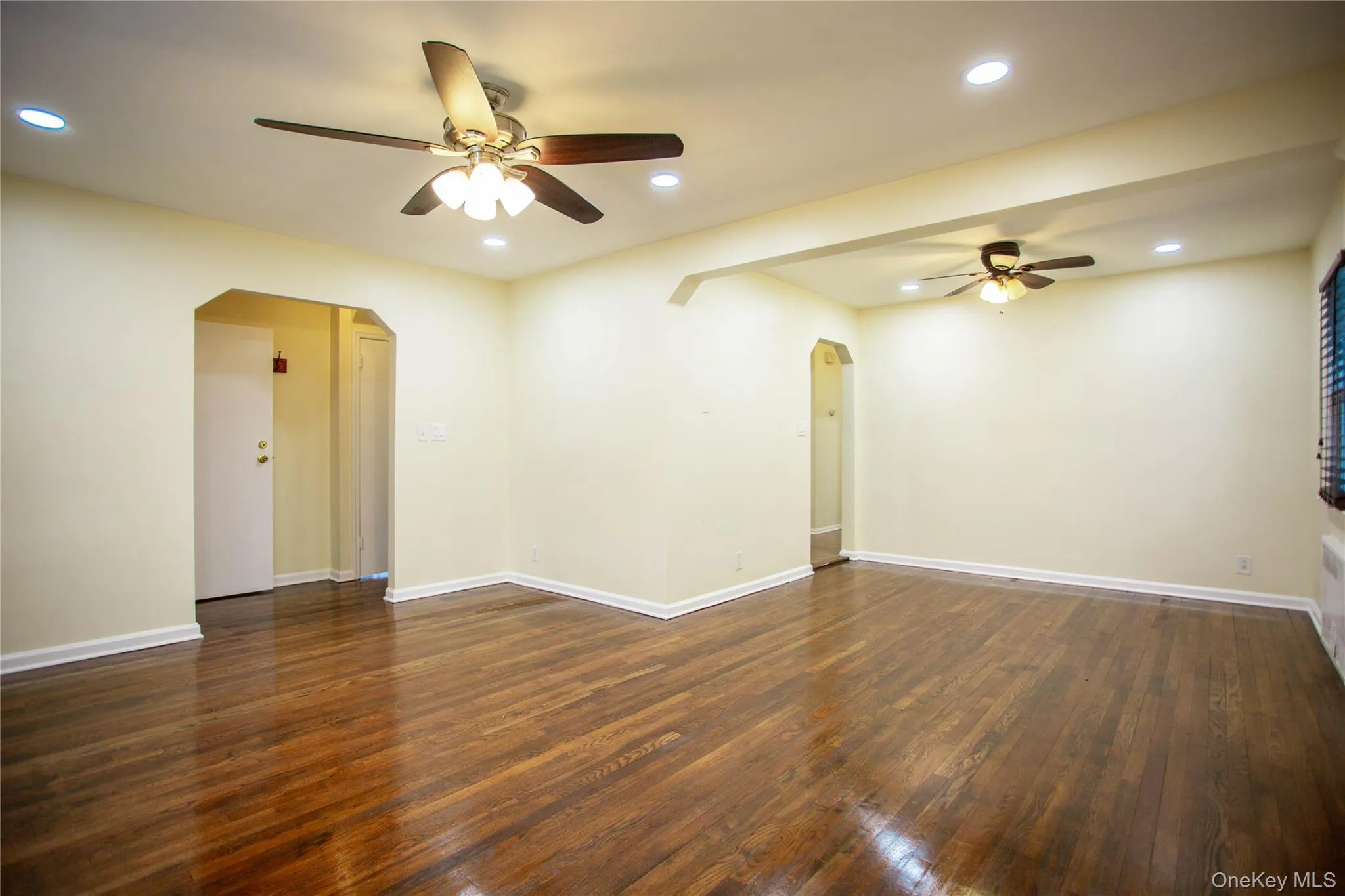 Empty room featuring recessed lighting, a ceiling fan, arched walkways, and dark wood-type flooring Empty room featuring recessed lighting, a ceiling fan, arched walkways, and dark wood-type flooring