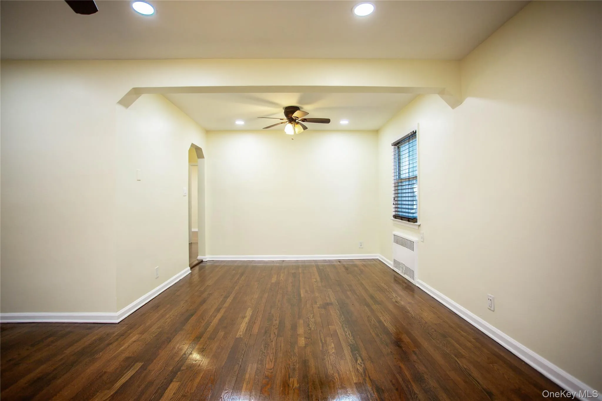 Empty room with arched walkways, a ceiling fan, radiator heating unit, and recessed lighting Empty room with arched walkways, a ceiling fan, radiator heating unit, and recessed lighting