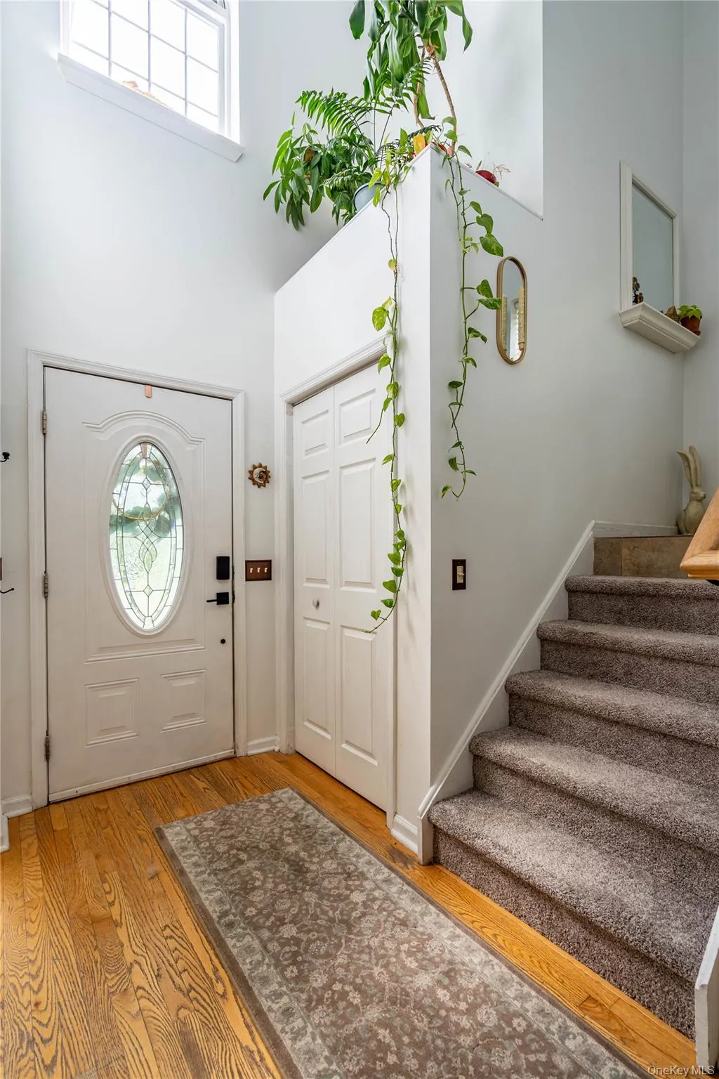 Entryway with light wood-style flooring, a towering ceiling, and stairway Entryway with light wood-style flooring, a towering ceiling, and stairway