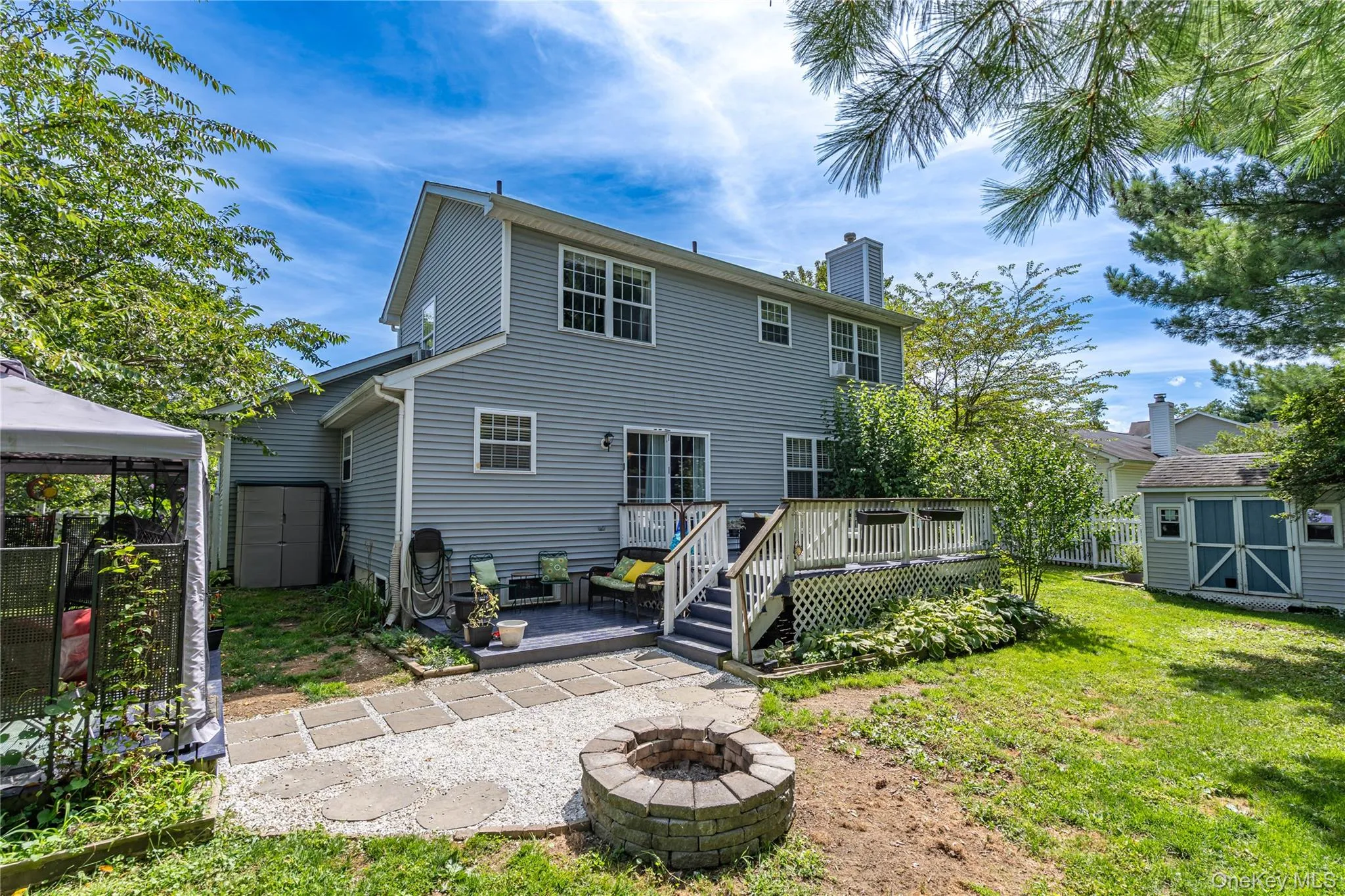 Back of house featuring a storage unit, a patio area, a fire pit, and a chimney Back of house featuring a storage unit, a patio area, a fire pit, and a chimney