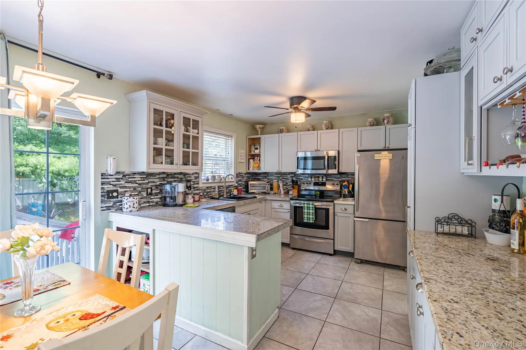 Kitchen with glass insert cabinets, appliances with stainless steel finishes, open shelves, and backsplash Kitchen with glass insert cabinets, appliances with stainless steel finishes, open shelves, and backsplash