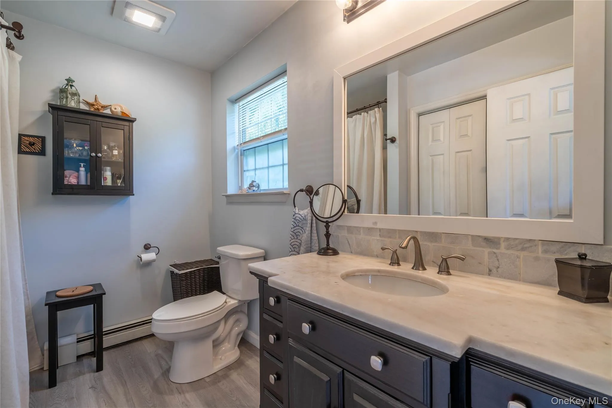 Bathroom with vanity, light wood finished floors, tasteful backsplash, and a baseboard radiator Bathroom with vanity, light wood finished floors, tasteful backsplash, and a baseboard radiator