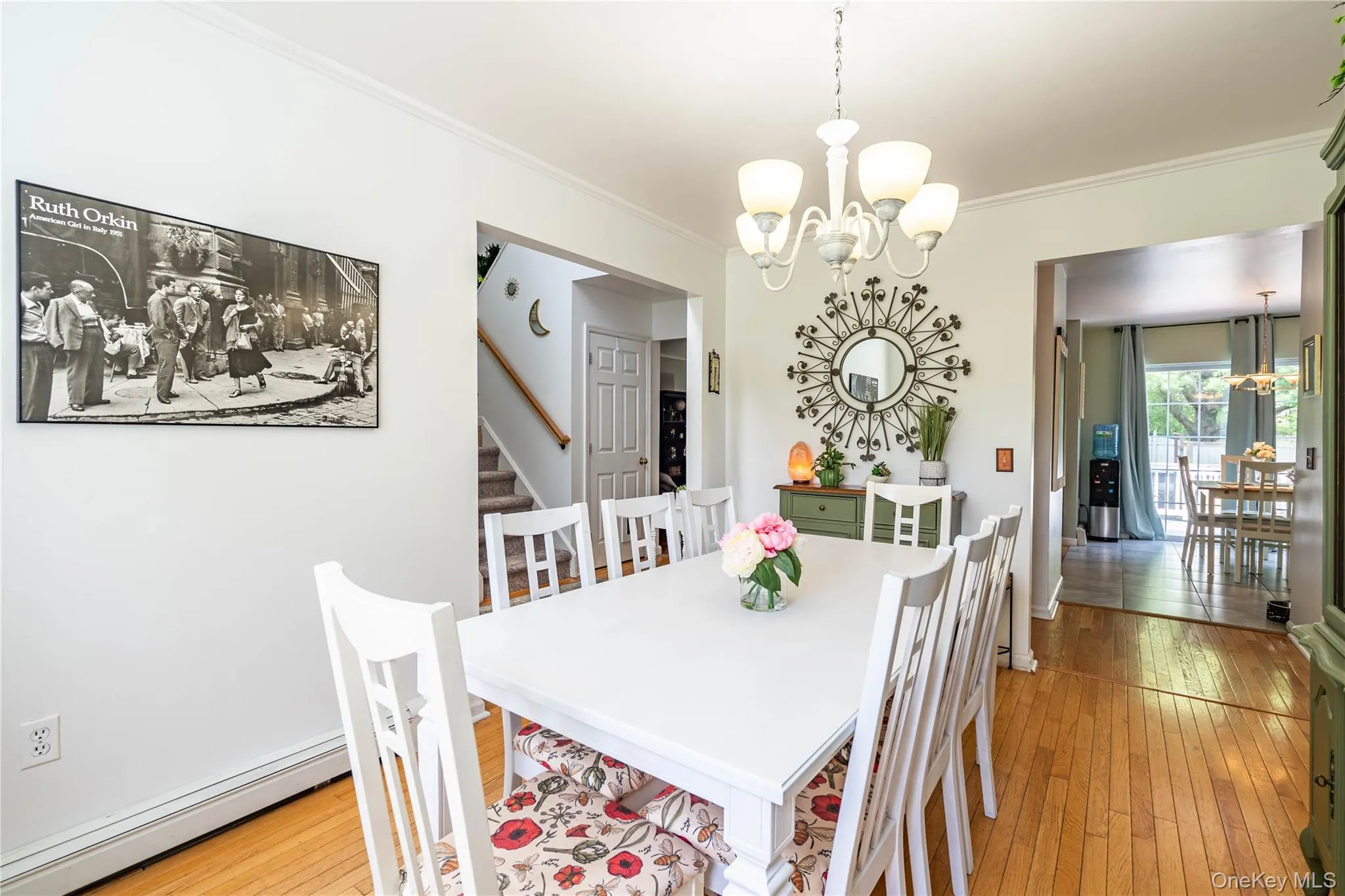 Dining space featuring a chandelier, baseboard heating, light wood-style flooring, crown molding, and stairway Dining space featuring a chandelier, baseboard heating, light wood-style flooring, crown molding, and stairway