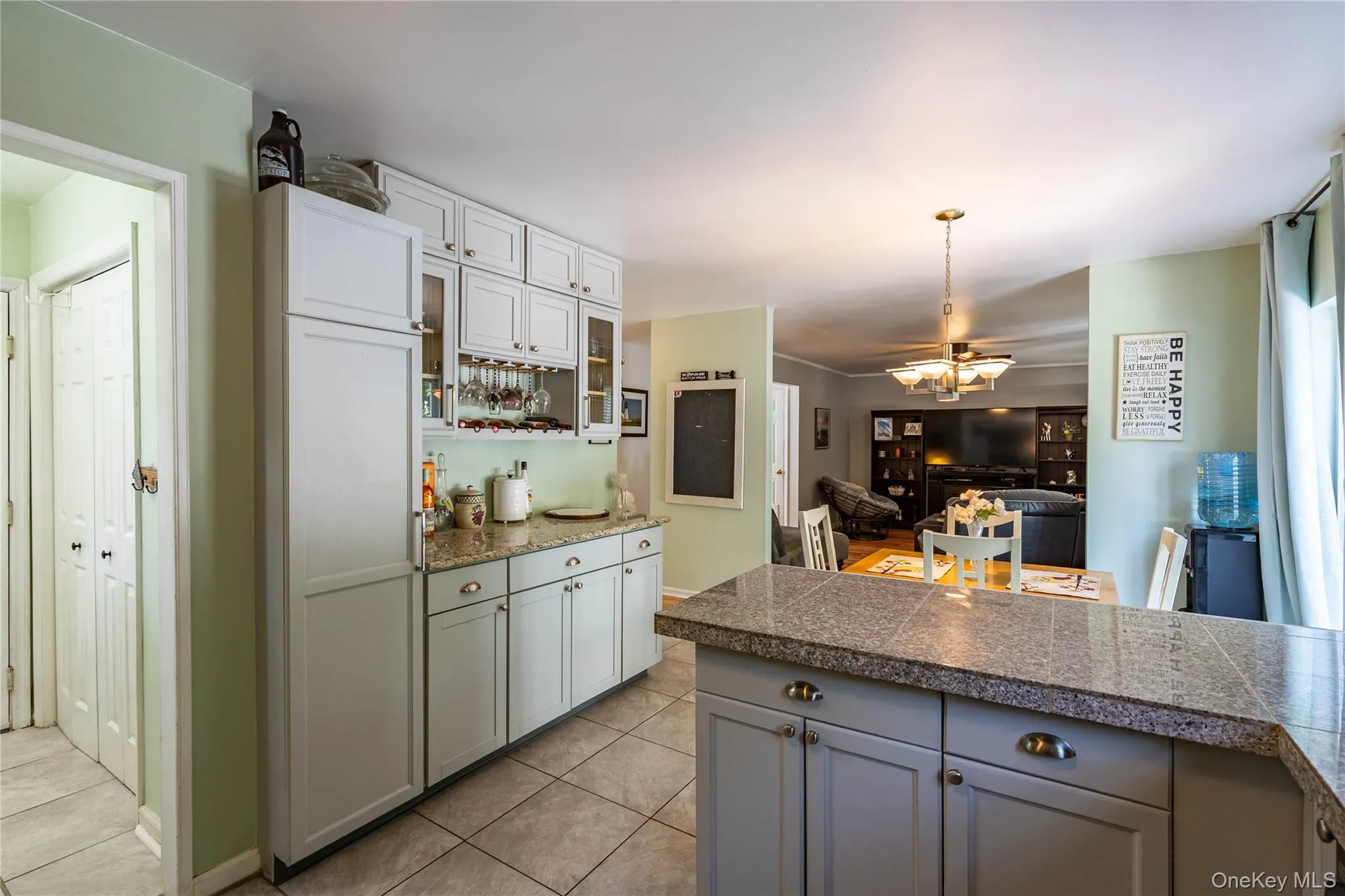 Kitchen featuring tile counters, decorative light fixtures, light tile patterned floors, open floor plan, and gray cabinetry Kitchen featuring tile counters, decorative light fixtures, light tile patterned floors, open floor plan, and gray cabinetry
