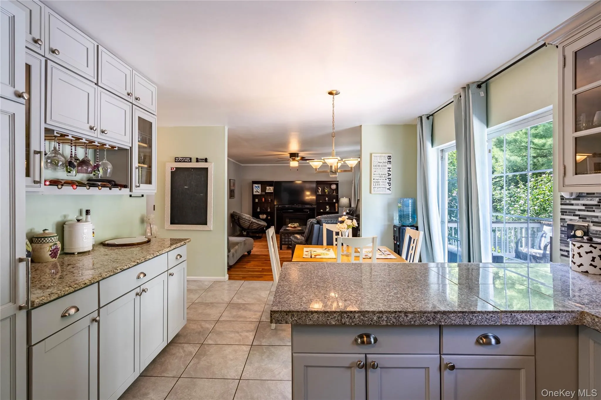 Kitchen with glass insert cabinets, tile countertops, decorative light fixtures, and light tile patterned floors Kitchen with glass insert cabinets, tile countertops, decorative light fixtures, and light tile patterned floors