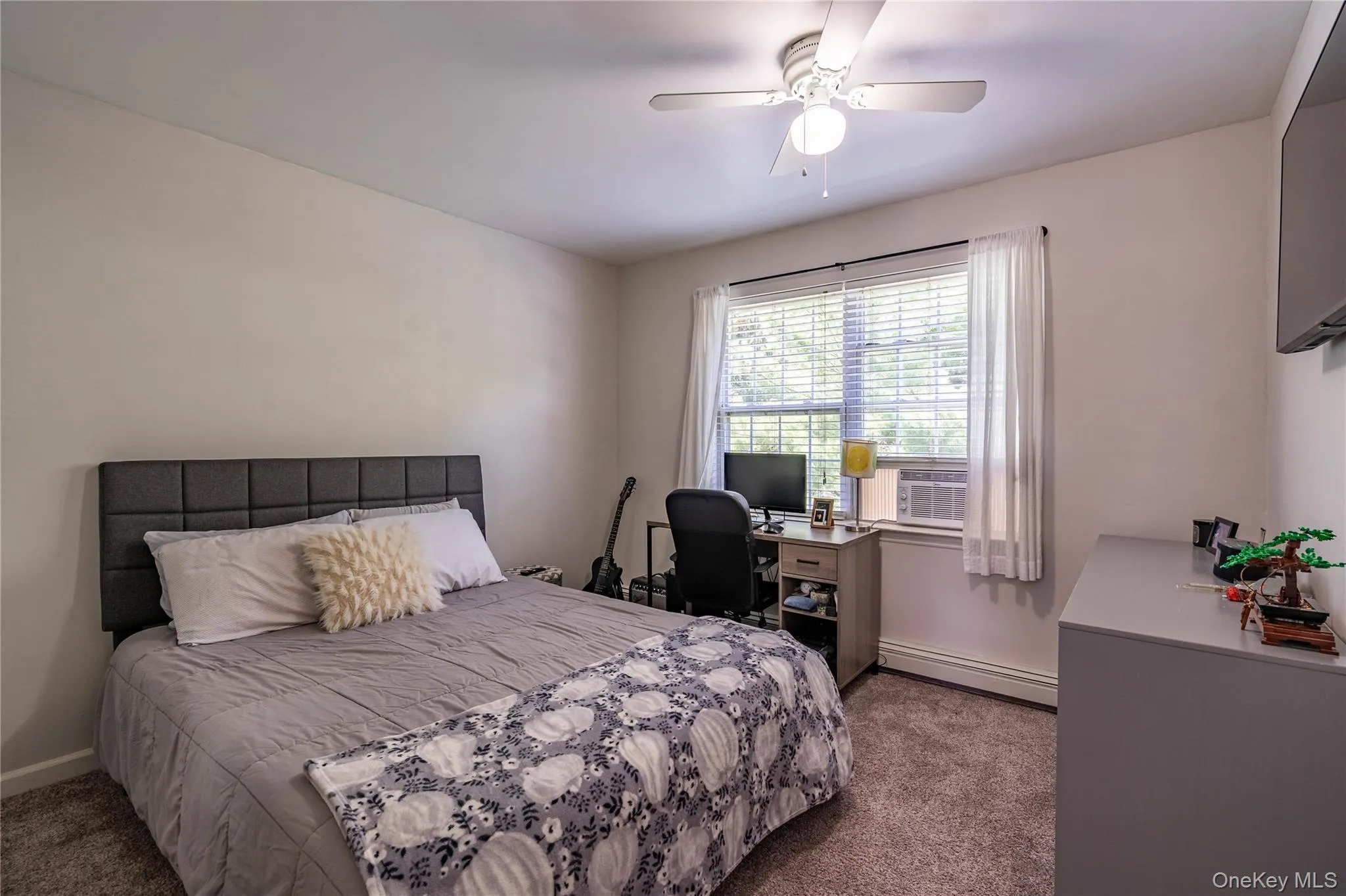 Carpeted bedroom with baseboard heating, ceiling fan, and cooling unit Carpeted bedroom with baseboard heating, ceiling fan, and cooling unit
