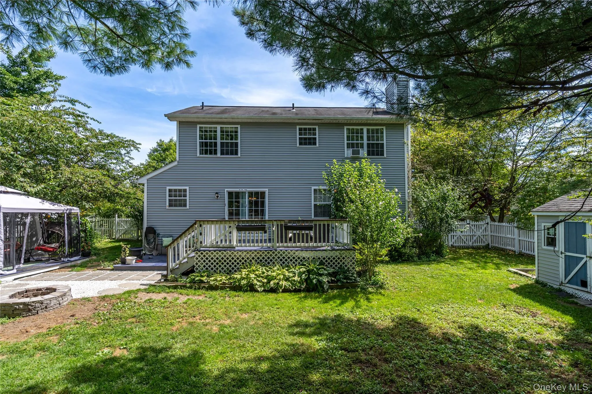 Back of house with a fenced backyard, an outdoor fire pit, a gazebo, a deck, and a patio Back of house with a fenced backyard, an outdoor fire pit, a gazebo, a deck, and a patio