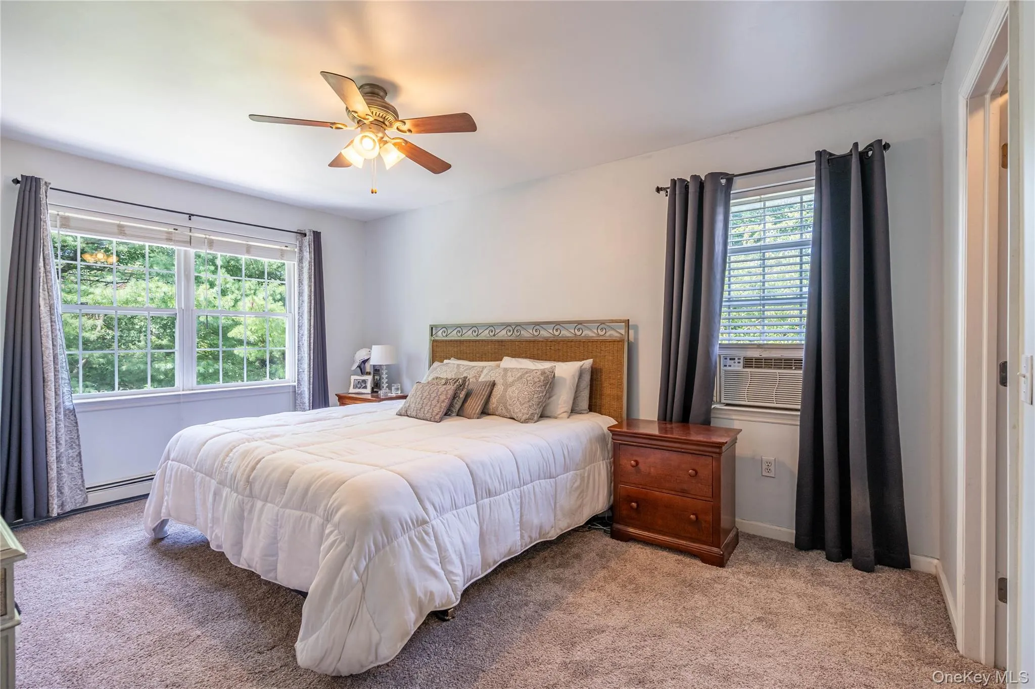 Carpeted bedroom featuring ceiling fan, a baseboard heating unit, and cooling unit Carpeted bedroom featuring ceiling fan, a baseboard heating unit, and cooling unit