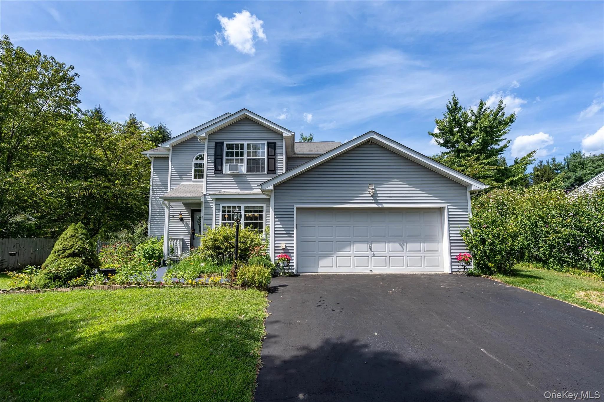 Traditional-style home with asphalt driveway, a front lawn, and an attached garage Traditional-style home with asphalt driveway, a front lawn, and an attached garage