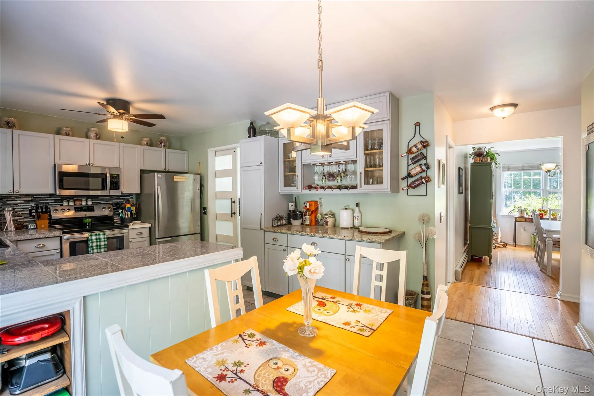 Kitchen with tile countertops, stainless steel appliances, backsplash, decorative light fixtures, and a chandelier Kitchen with tile countertops, stainless steel appliances, backsplash, decorative light fixtures, and a chandelier