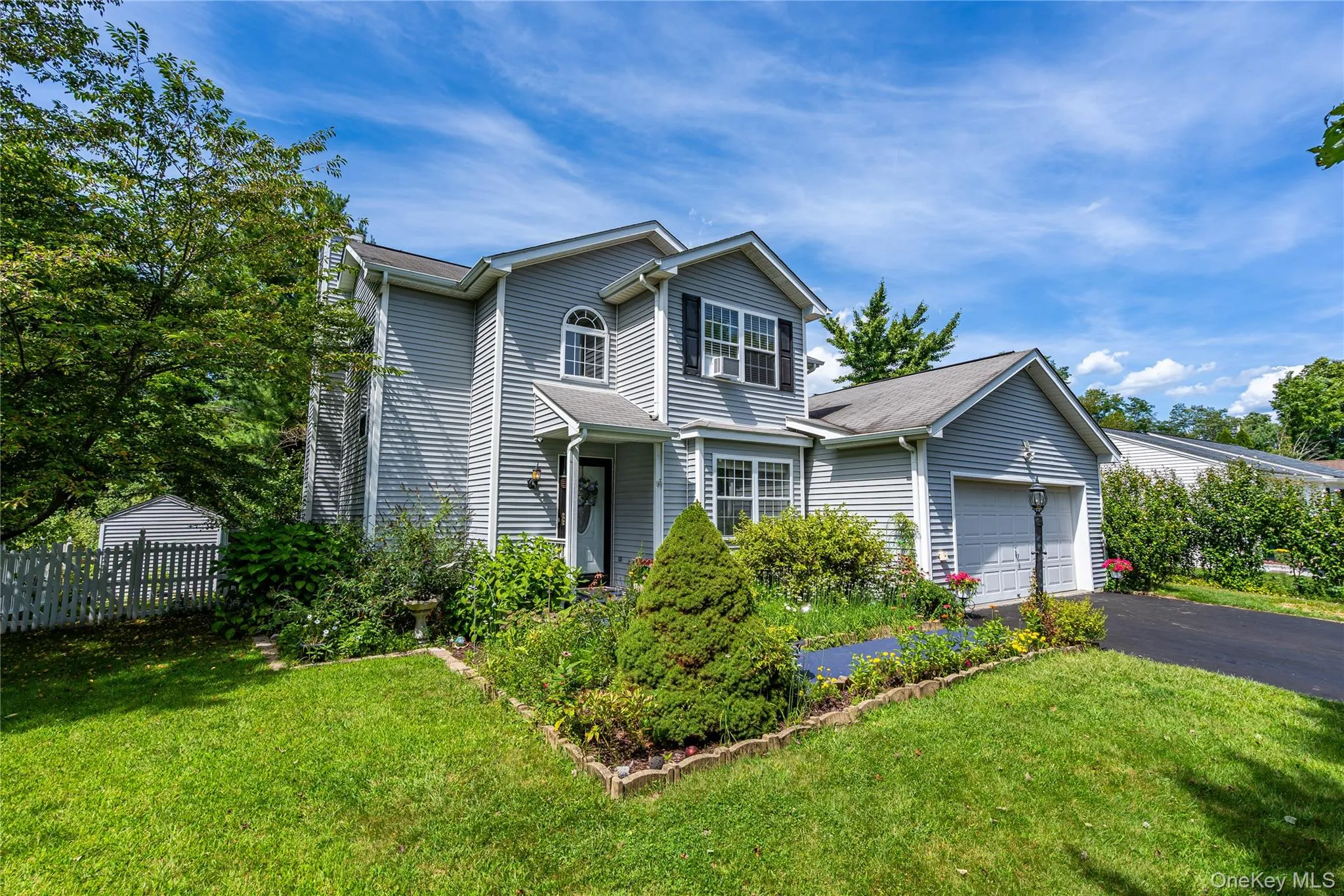 Traditional home featuring asphalt driveway and an attached garage Traditional home featuring asphalt driveway and an attached garage