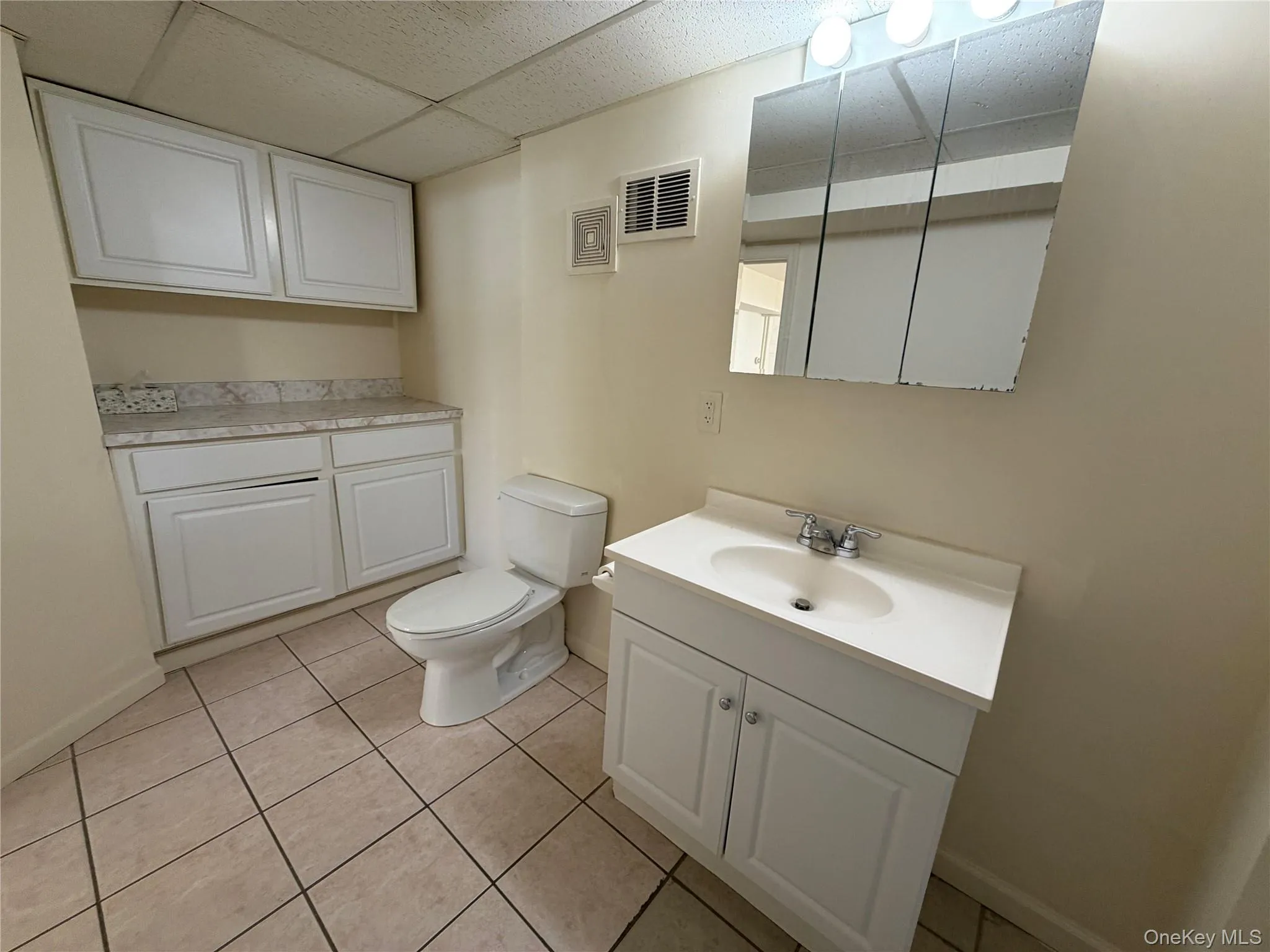 Bathroom with light tile patterned flooring, a paneled ceiling, and vanity Bathroom with light tile patterned flooring, a paneled ceiling, and vanity