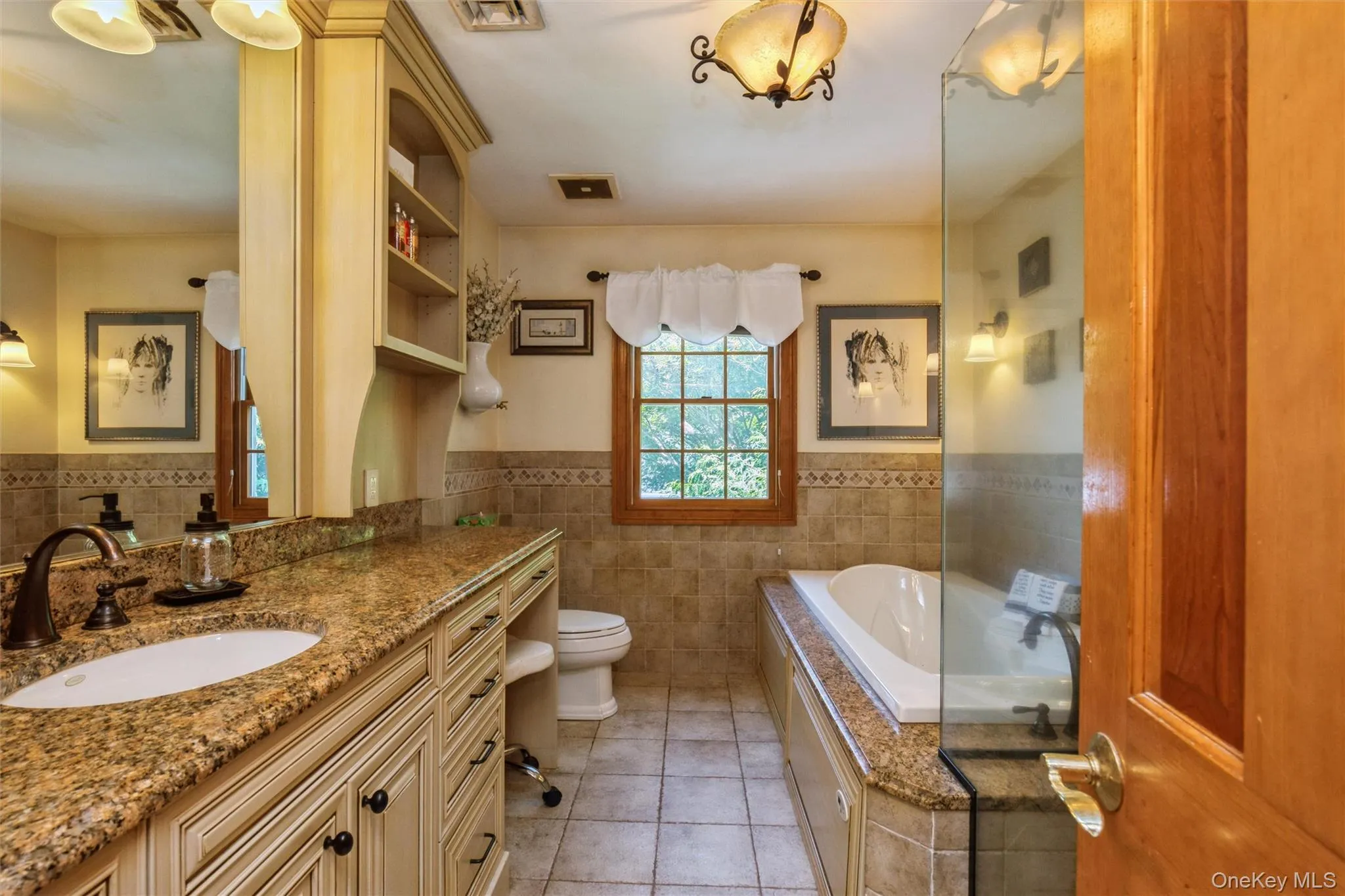 Bathroom featuring an extended vanity with a granite countertop, and cream-colored cabinetry Bathroom featuring an extended vanity with a granite countertop, and cream-colored cabinetry