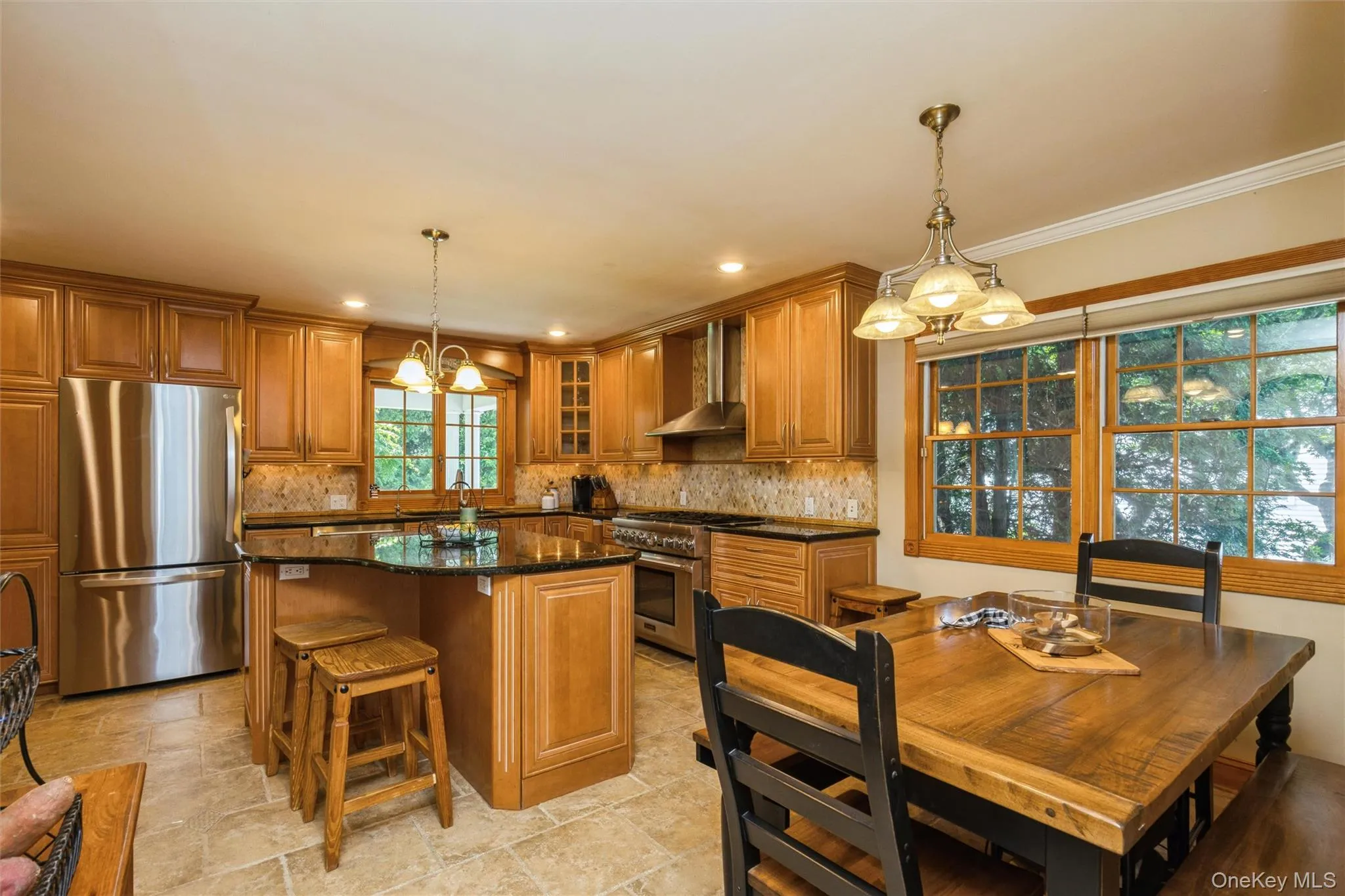 Kitchen with wood cabinetry, stainless steel appliances, and a central island featuring granite countertop Kitchen with wood cabinetry, stainless steel appliances, and a central island featuring granite countertop