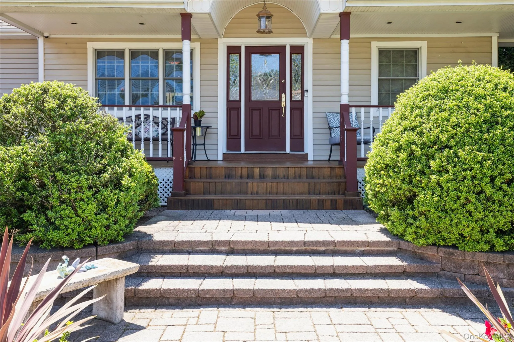 Inviting front entrance featuring a richly stained door with decorative glass, flanked by classic white-framed windows Inviting front entrance featuring a richly stained door with decorative glass, flanked by classic white-framed windows