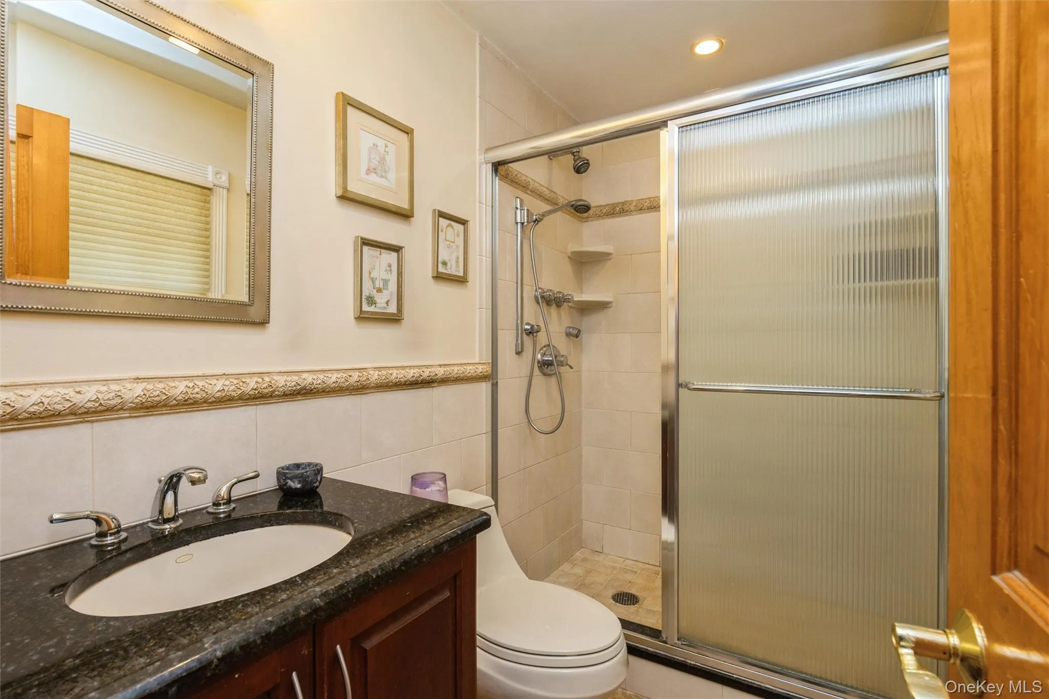 Bathroom featuring a dark wood vanity with a stone countertop, an undermount sink, and a framed mirror Bathroom featuring a dark wood vanity with a stone countertop, an undermount sink, and a framed mirror