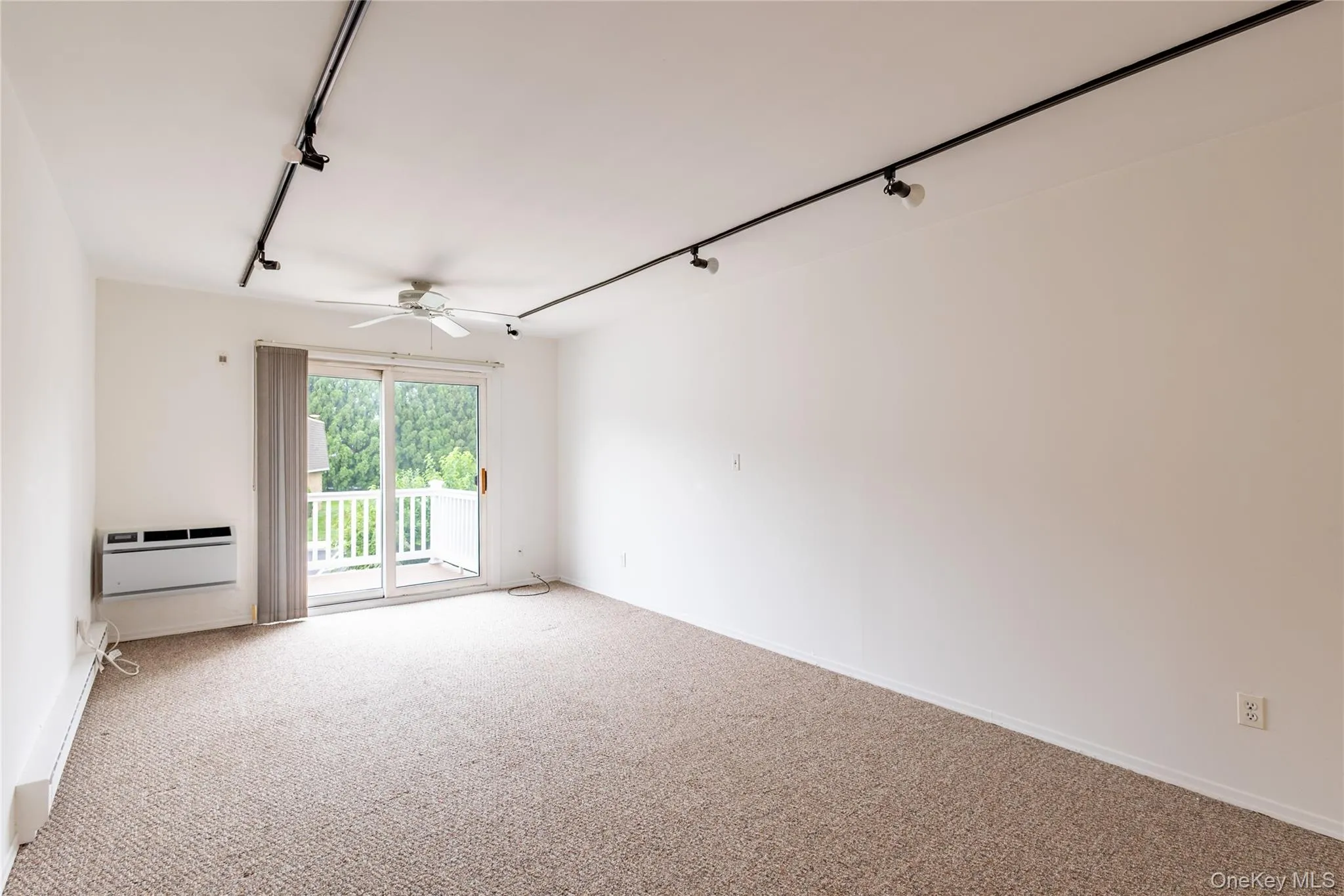 Very large living room with overhead lighting, fresh carpet, neutral paint, wall ac unit, and slider to balcony Very large living room with overhead lighting, fresh carpet, neutral paint, wall ac unit, and slider to balcony