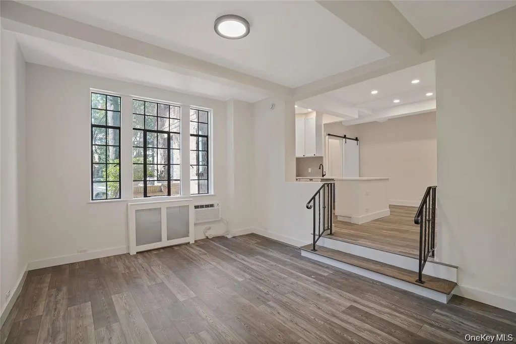 Spacious room featuring wood-finish flooring, crisp white walls, and elegant crown molding Spacious room featuring wood-finish flooring, crisp white walls, and elegant crown molding