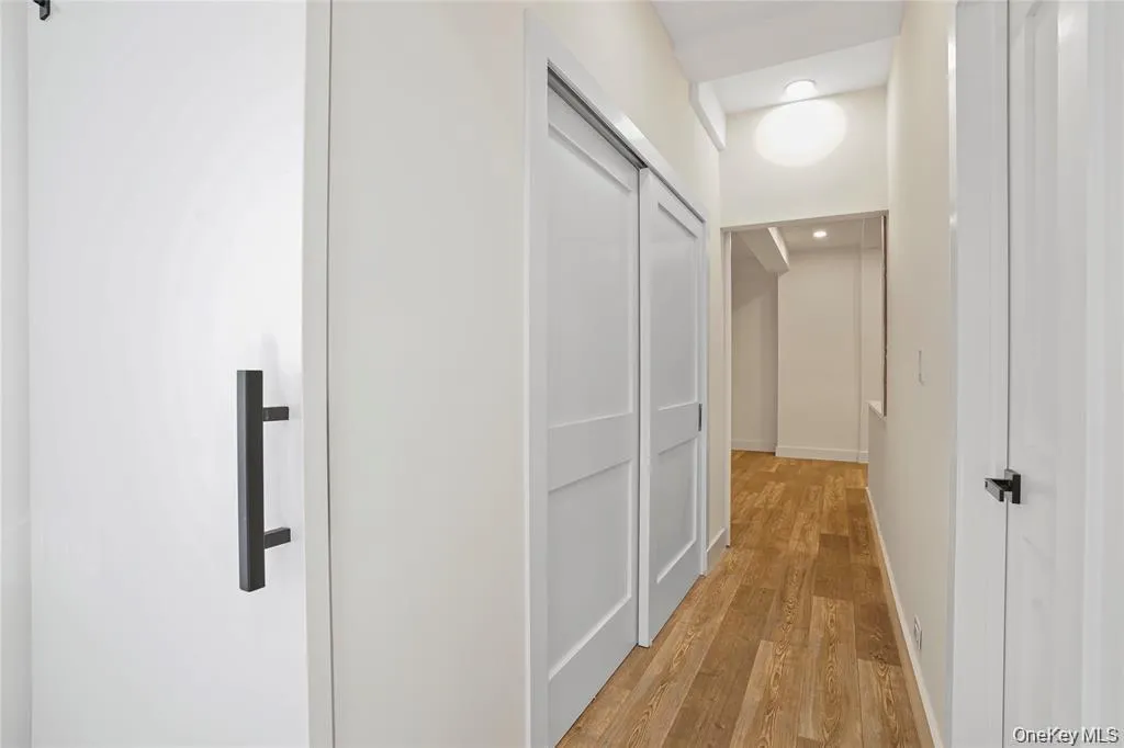 Hallway featuring wood-finish flooring, white walls, and recessed lighting Hallway featuring wood-finish flooring, white walls, and recessed lighting