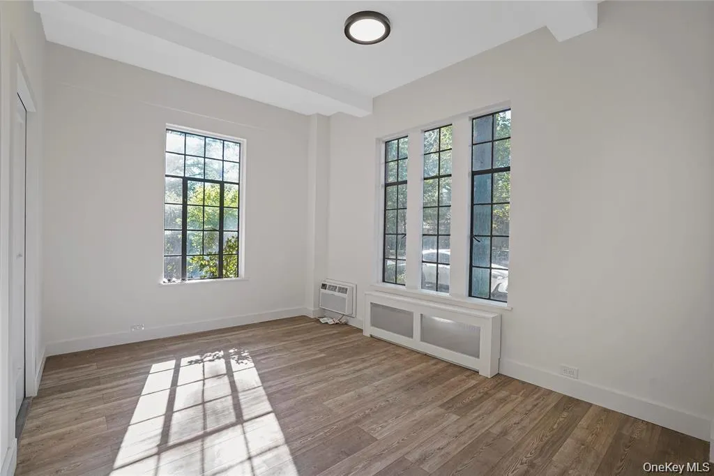 Spacious interior featuring wood-finish flooring, white walls, and a large multi-pane window with exterior views Spacious interior featuring wood-finish flooring, white walls, and a large multi-pane window with exterior views
