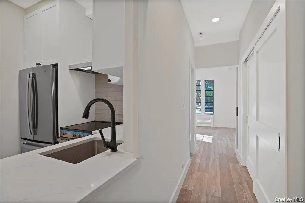 Hallway featuring wood-finish flooring, white walls, and recessed lighting Hallway featuring wood-finish flooring, white walls, and recessed lighting