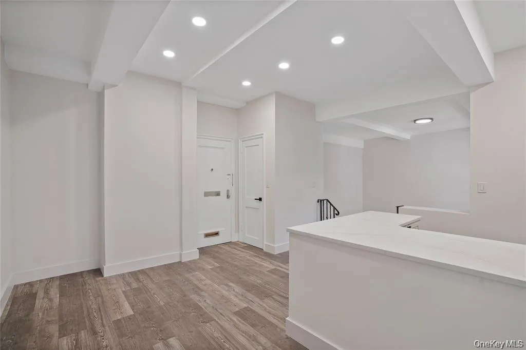 Open-concept living space featuring wood-finish flooring, a contemporary kitchen island with a white countertop, and recessed lighting Open-concept living space featuring wood-finish flooring, a contemporary kitchen island with a white countertop, and recessed lighting