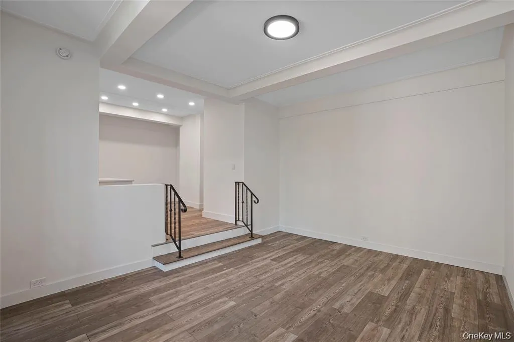 Spacious room featuring wood-finish flooring, crisp white walls, and elegant crown molding Spacious room featuring wood-finish flooring, crisp white walls, and elegant crown molding