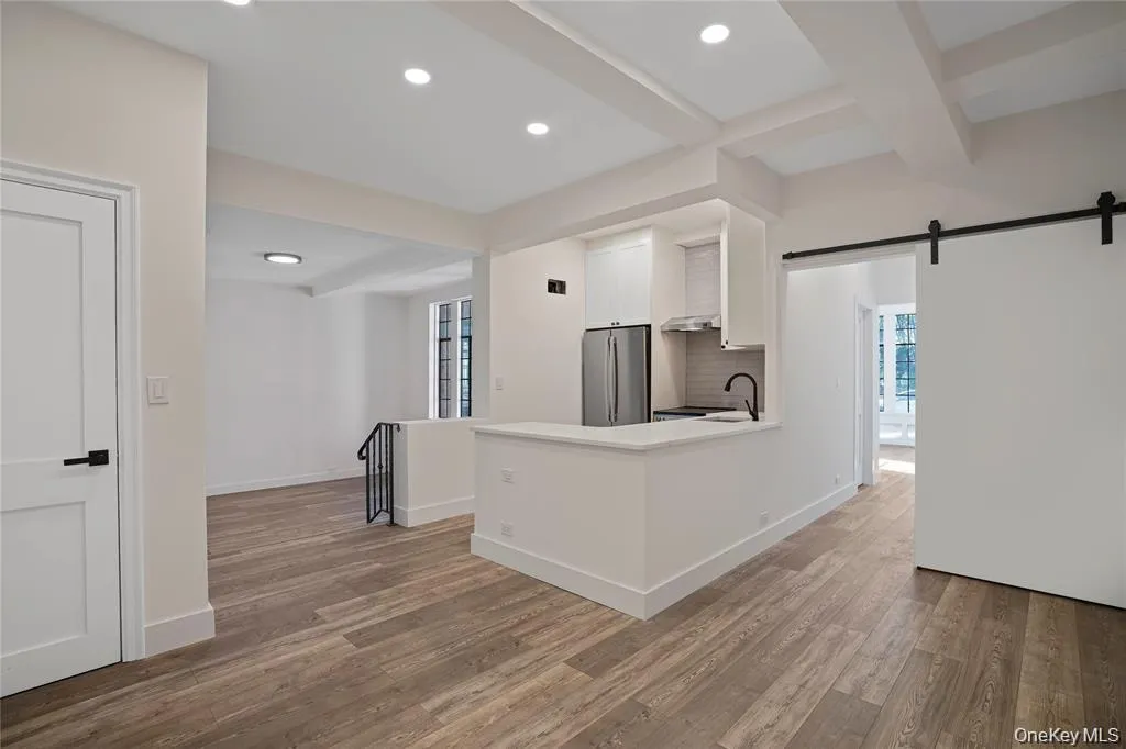 Open-concept living space featuring wood-finish flooring, a contemporary kitchen island with a white countertop, and recessed lighting Open-concept living space featuring wood-finish flooring, a contemporary kitchen island with a white countertop, and recessed lighting