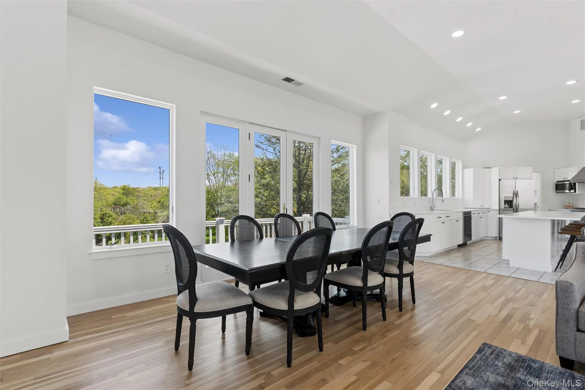 2nd Floor Spacious dining area with light wood-finish flooring, abundant natural light from multiple windows, and direct outdoor access through French doors 2nd Floor Spacious dining area with light wood-finish flooring, abundant natural light from multiple windows, and direct outdoor access through French doors