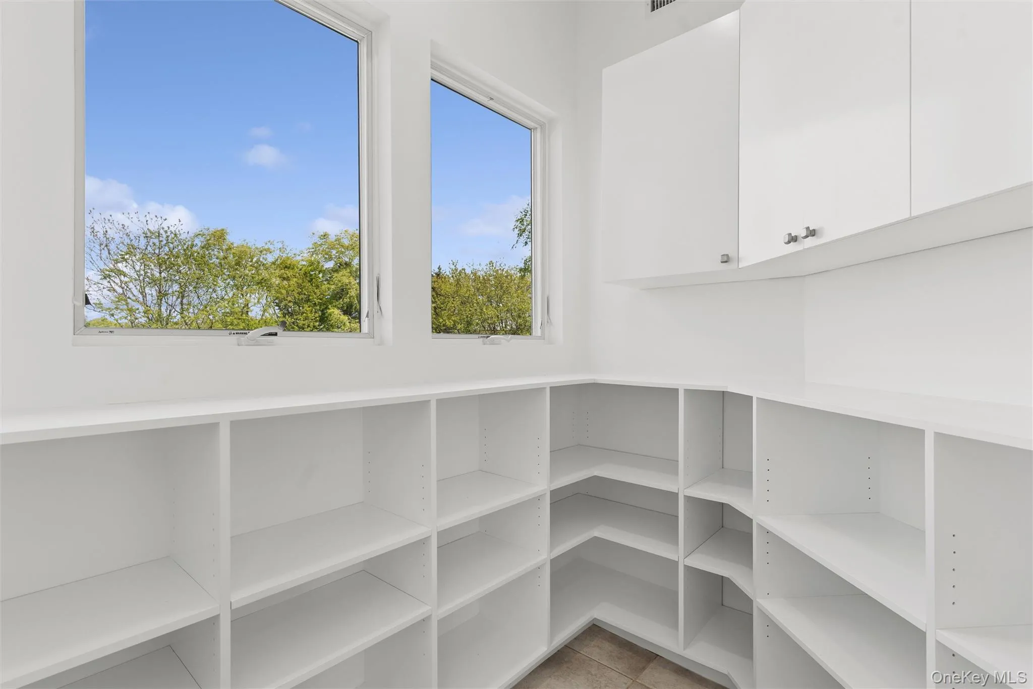 2nd Floor kitchen pantry with Expansive storage room featuring floor-to-ceiling white shelving, white upper cabinetry with silver hardware, and two large windows 2nd Floor kitchen pantry with Expansive storage room featuring floor-to-ceiling white shelving, white upper cabinetry with silver hardware, and two large windows