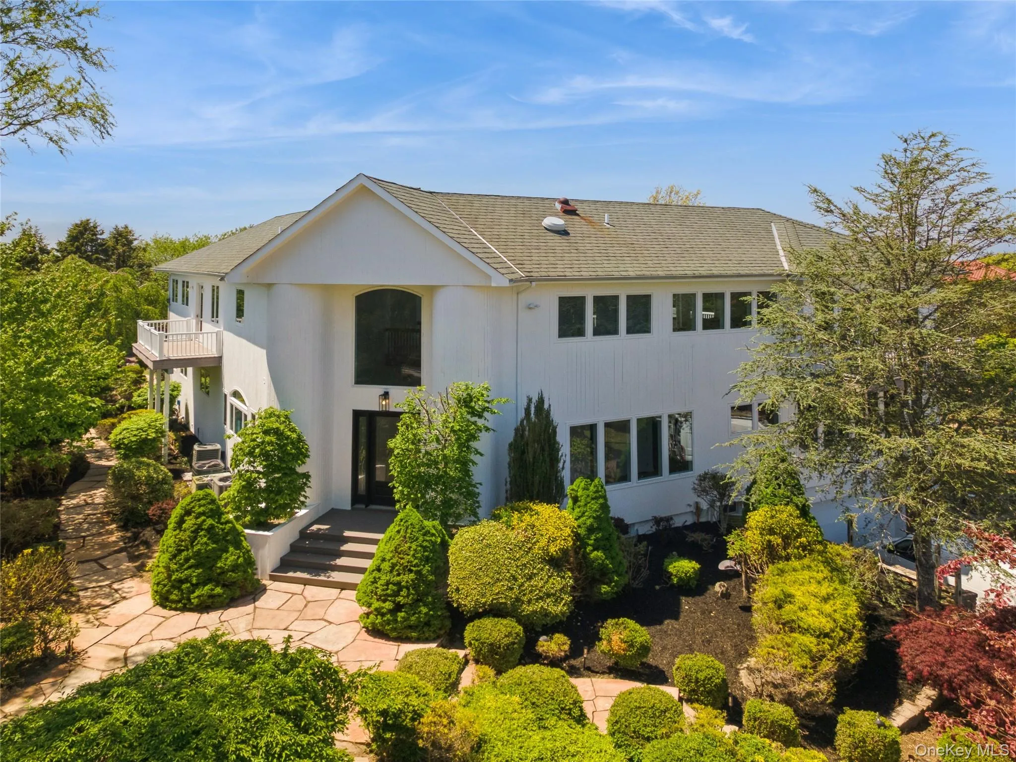 Contemporary residence featuring a prominent arched window, white exterior siding, and a gabled roof Contemporary residence featuring a prominent arched window, white exterior siding, and a gabled roof