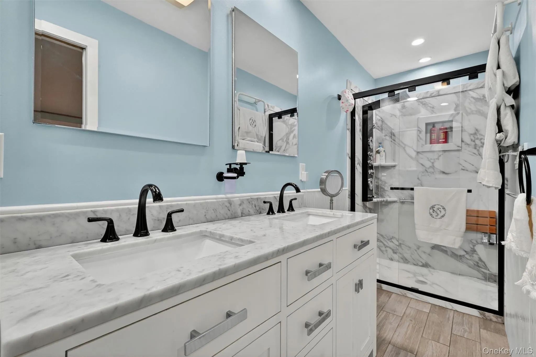 Beautifully updated primary bath showcasing a double vanity with quartz countertop, modern fixtures, and a custom tiled walk-in shower. Beautifully updated primary bath showcasing a double vanity with quartz countertop, modern fixtures, and a custom tiled walk-in shower.
