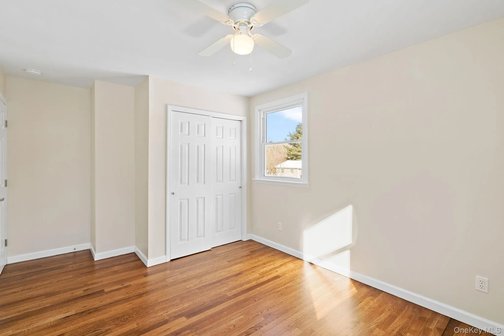 Unfurnished bedroom with wood-type flooring, ceiling fan, and a closet Unfurnished bedroom with wood-type flooring, ceiling fan, and a closet