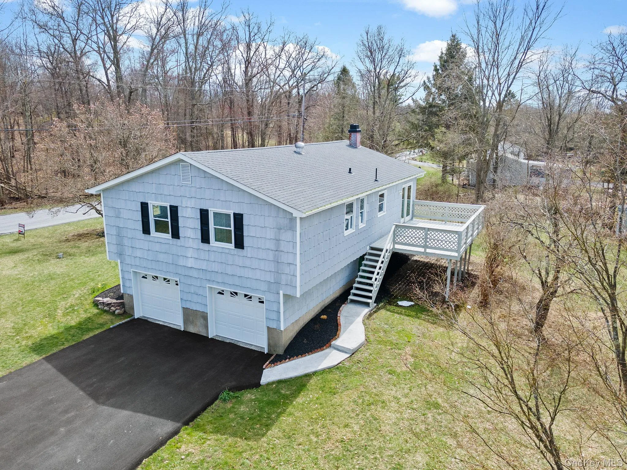 View of side of property with stairway, aphalt driveway, a wooden deck, a lawn, and roof with shingles View of side of property with stairway, aphalt driveway, a wooden deck, a lawn, and roof with shingles