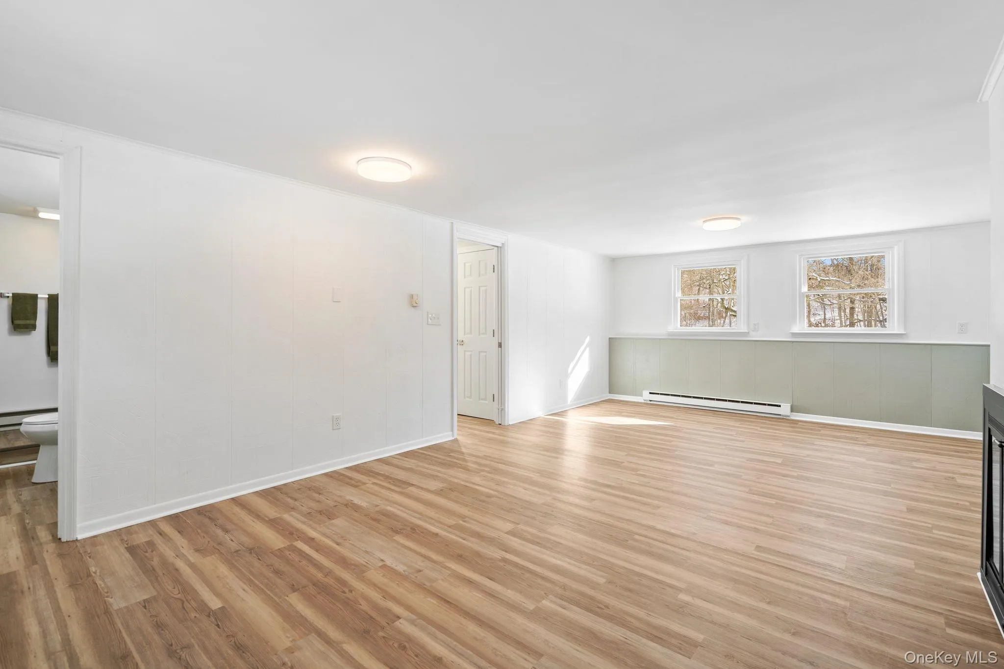 Empty room featuring light wood-type flooring and a baseboard heating unit Empty room featuring light wood-type flooring and a baseboard heating unit