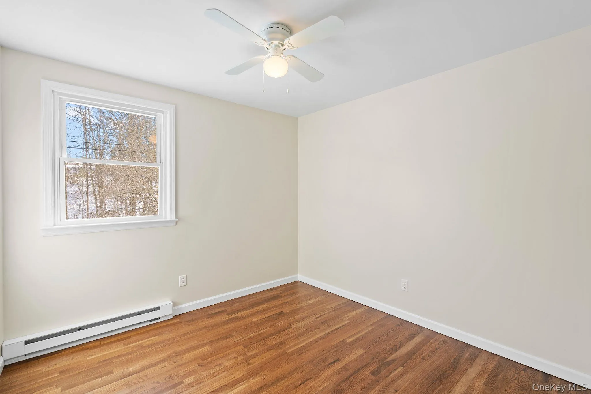 Unfurnished room with hardwood / wood-style flooring, a baseboard radiator, and ceiling fan Unfurnished room with hardwood / wood-style flooring, a baseboard radiator, and ceiling fan