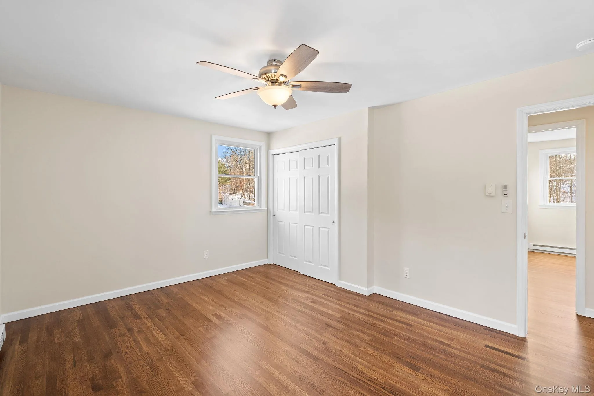 Unfurnished bedroom with a baseboard heating unit, hardwood / wood-style floors, a closet, and ceiling fan Unfurnished bedroom with a baseboard heating unit, hardwood / wood-style floors, a closet, and ceiling fan