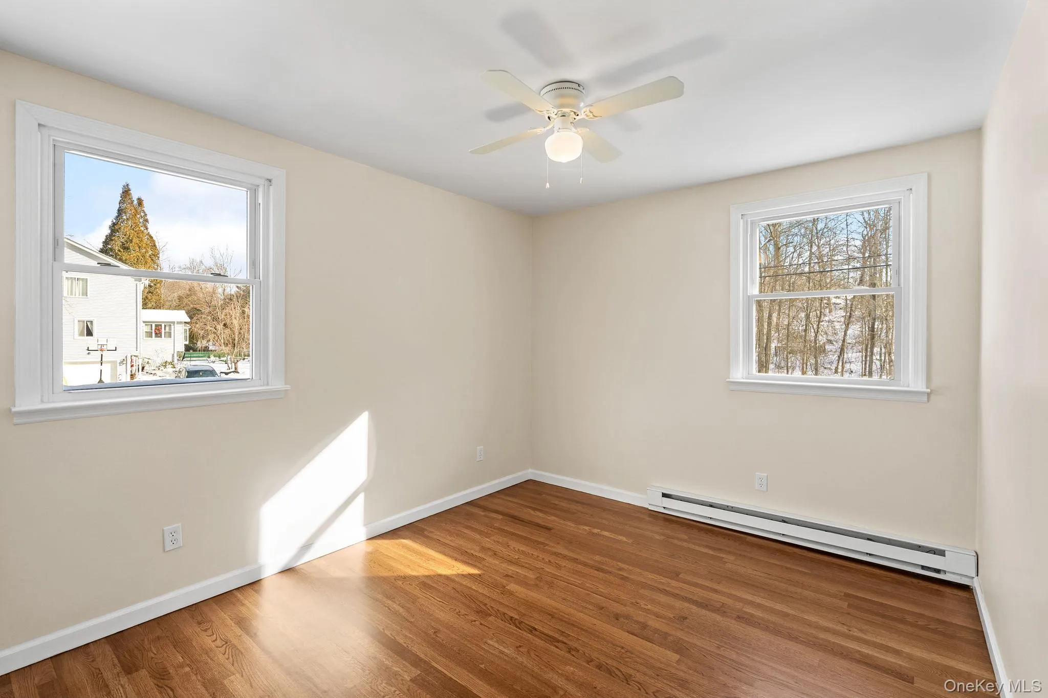 Unfurnished room with ceiling fan, a baseboard radiator, plenty of natural light, and wood-type flooring Unfurnished room with ceiling fan, a baseboard radiator, plenty of natural light, and wood-type flooring