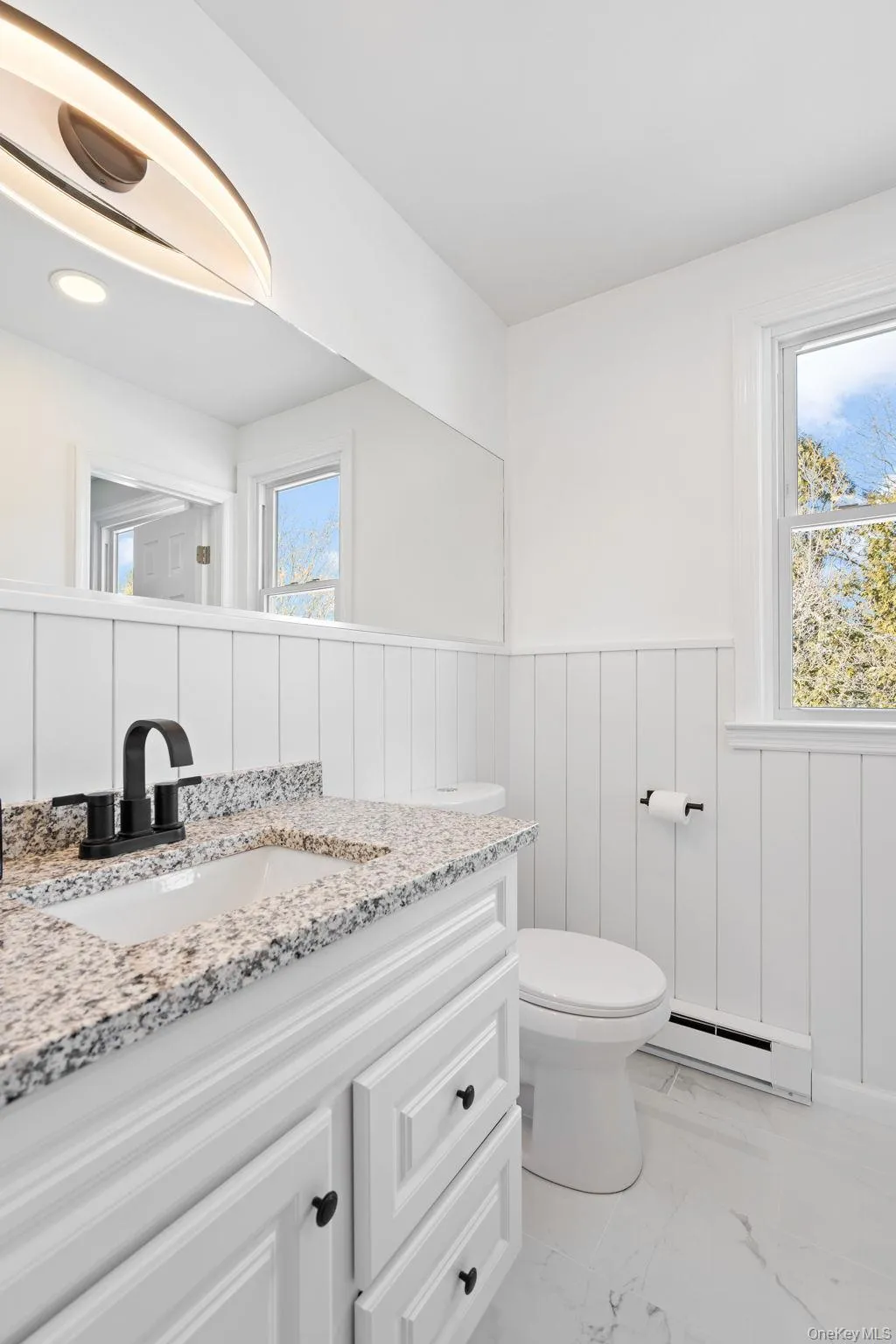 Bathroom with a baseboard radiator, plenty of natural light, vanity, and toilet Bathroom with a baseboard radiator, plenty of natural light, vanity, and toilet
