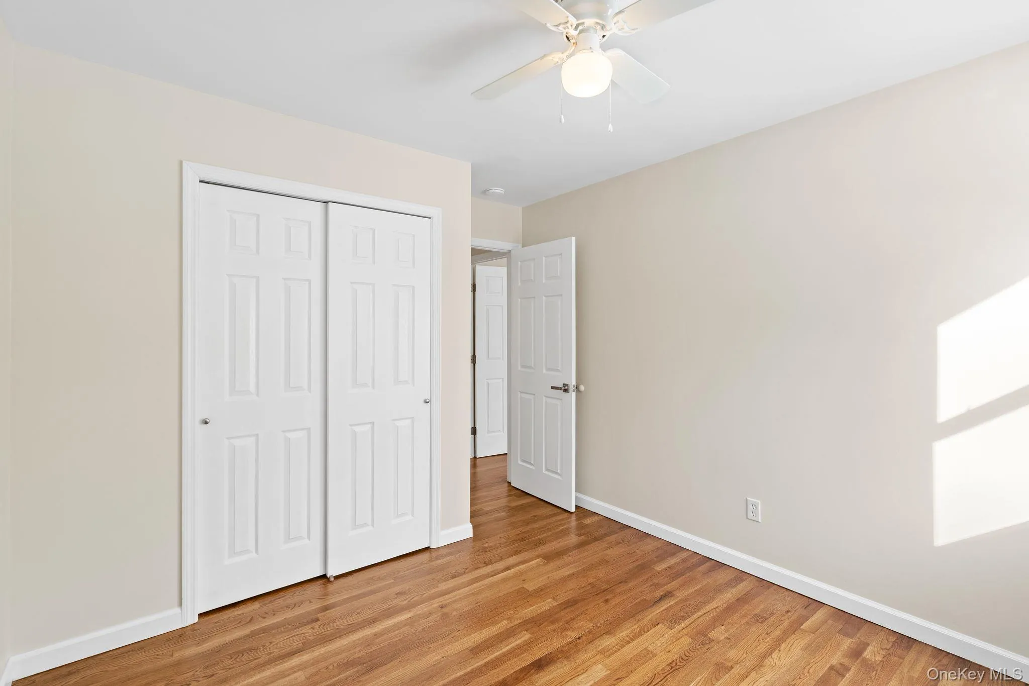 Unfurnished bedroom with ceiling fan, a closet, and light wood-type flooring Unfurnished bedroom with ceiling fan, a closet, and light wood-type flooring